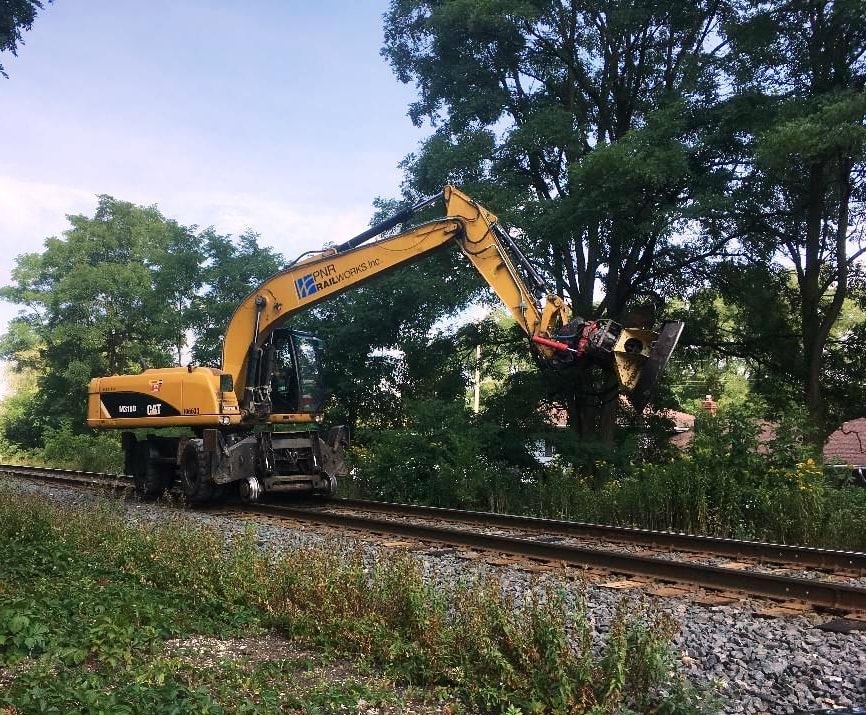Image of a large tree removing machine working on a rail line.