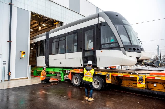 The first LRV is slowly offloaded from the flatbed of a truck by crews.