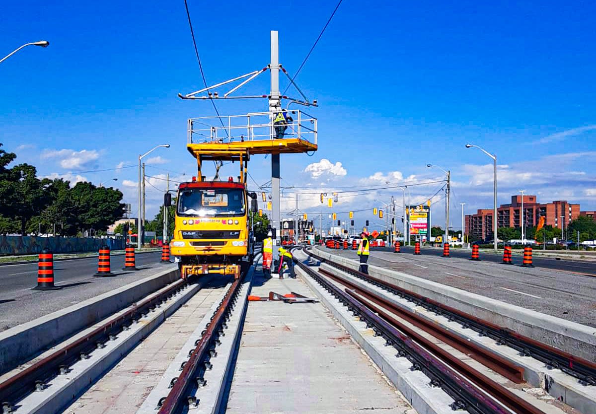 construction teams using a specialized rail mounted vehicle for installing things high up,