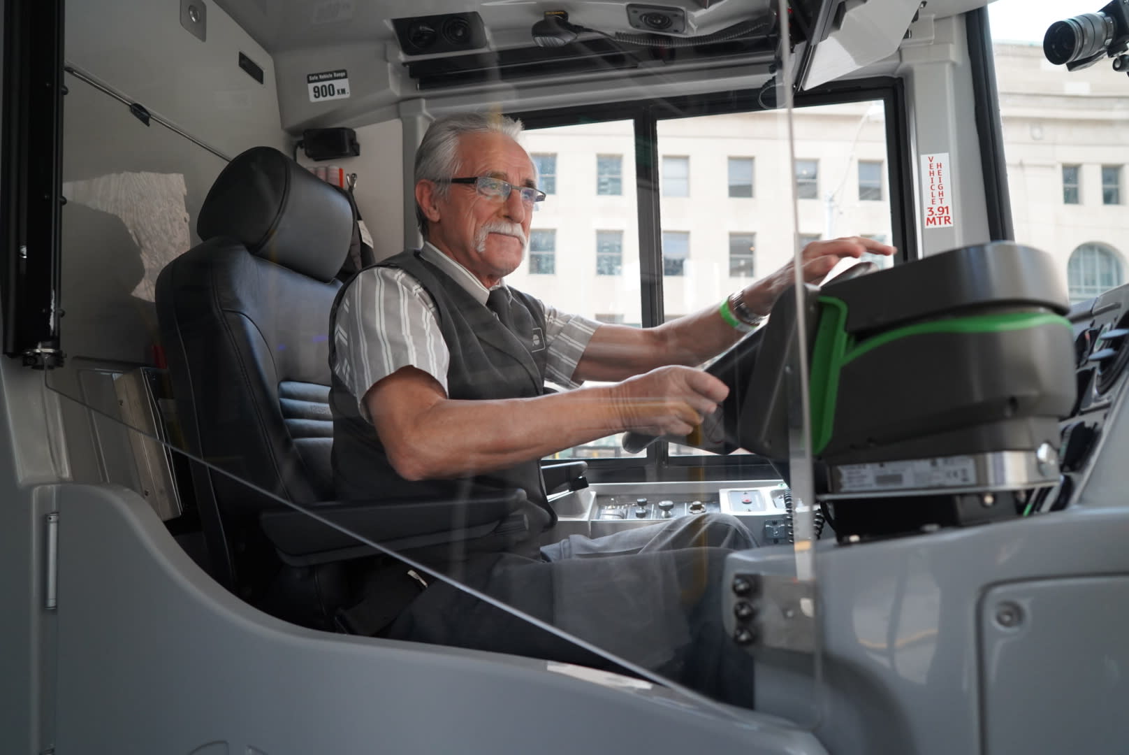 a bus driver with hands on the wheel, circled by a clear barrier.
