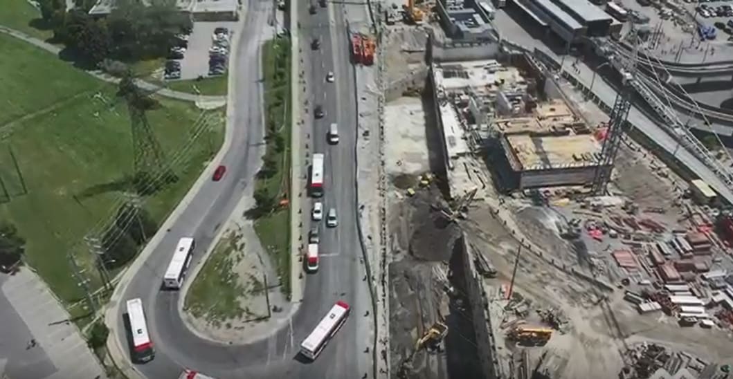 Image is shot from above, and shows the construction area, with buses moving nearby.