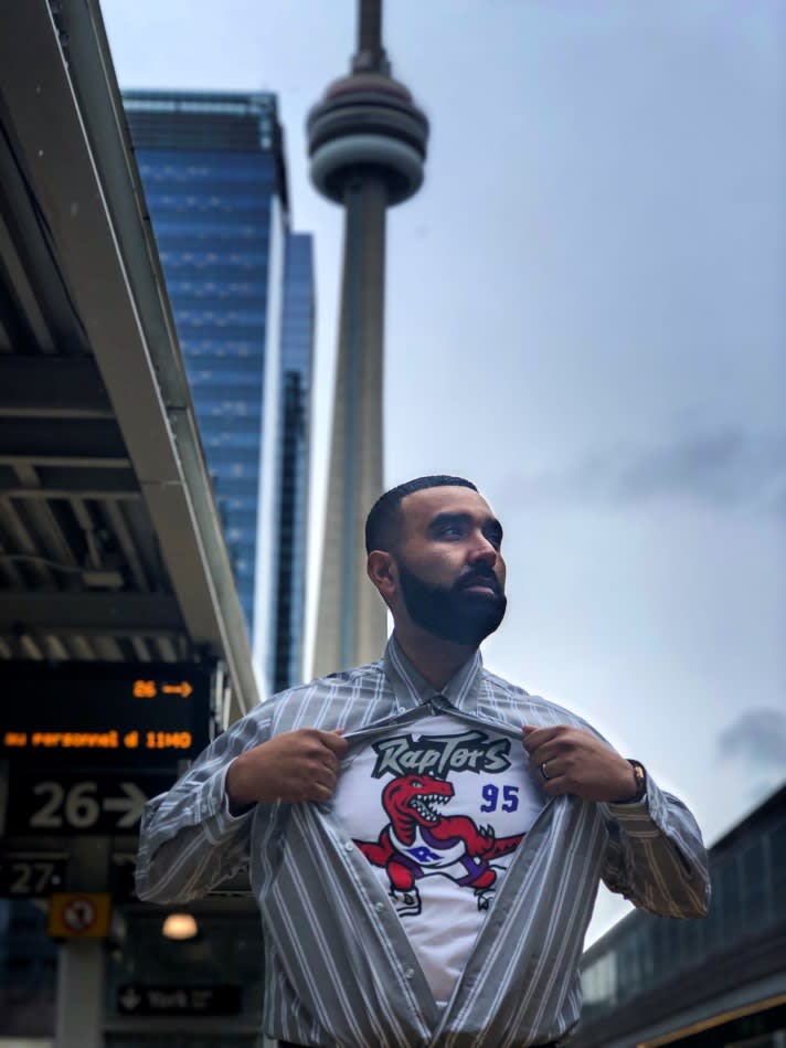 Khan opens up his GO uniform shirt to show a Raptors T-shirt underneath.