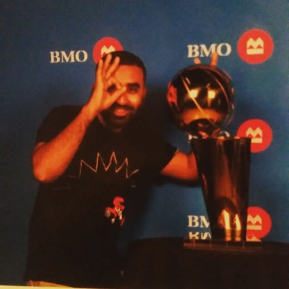 Khan beams as he poses next to the NBA championship trophy.
