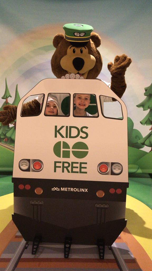 Two children post behind a cutout of a GO train.