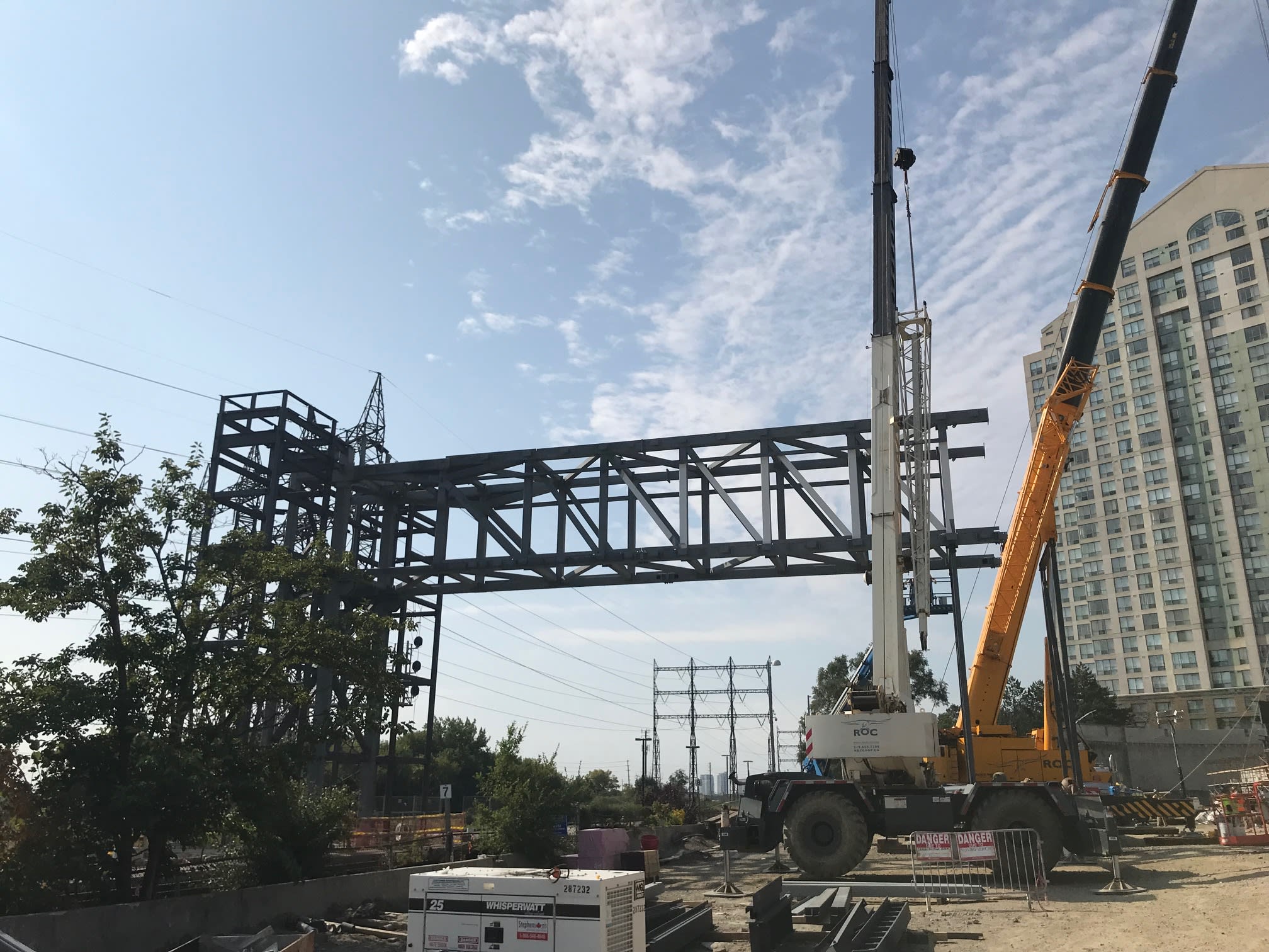 A large metal skeleton structure of a bridge is lifted with a big crane