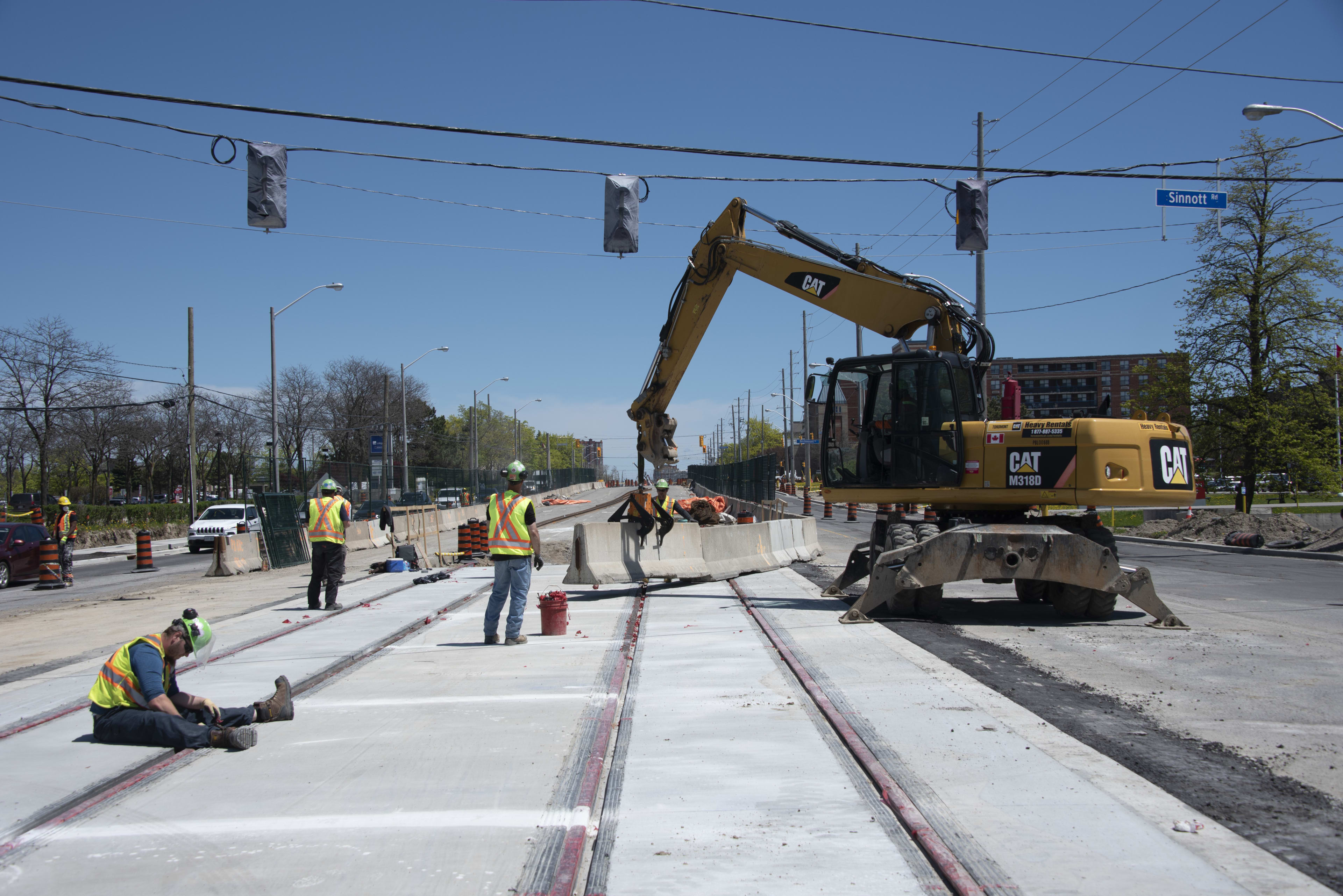 A large tractor moves a large concrete barrier over rail lines.