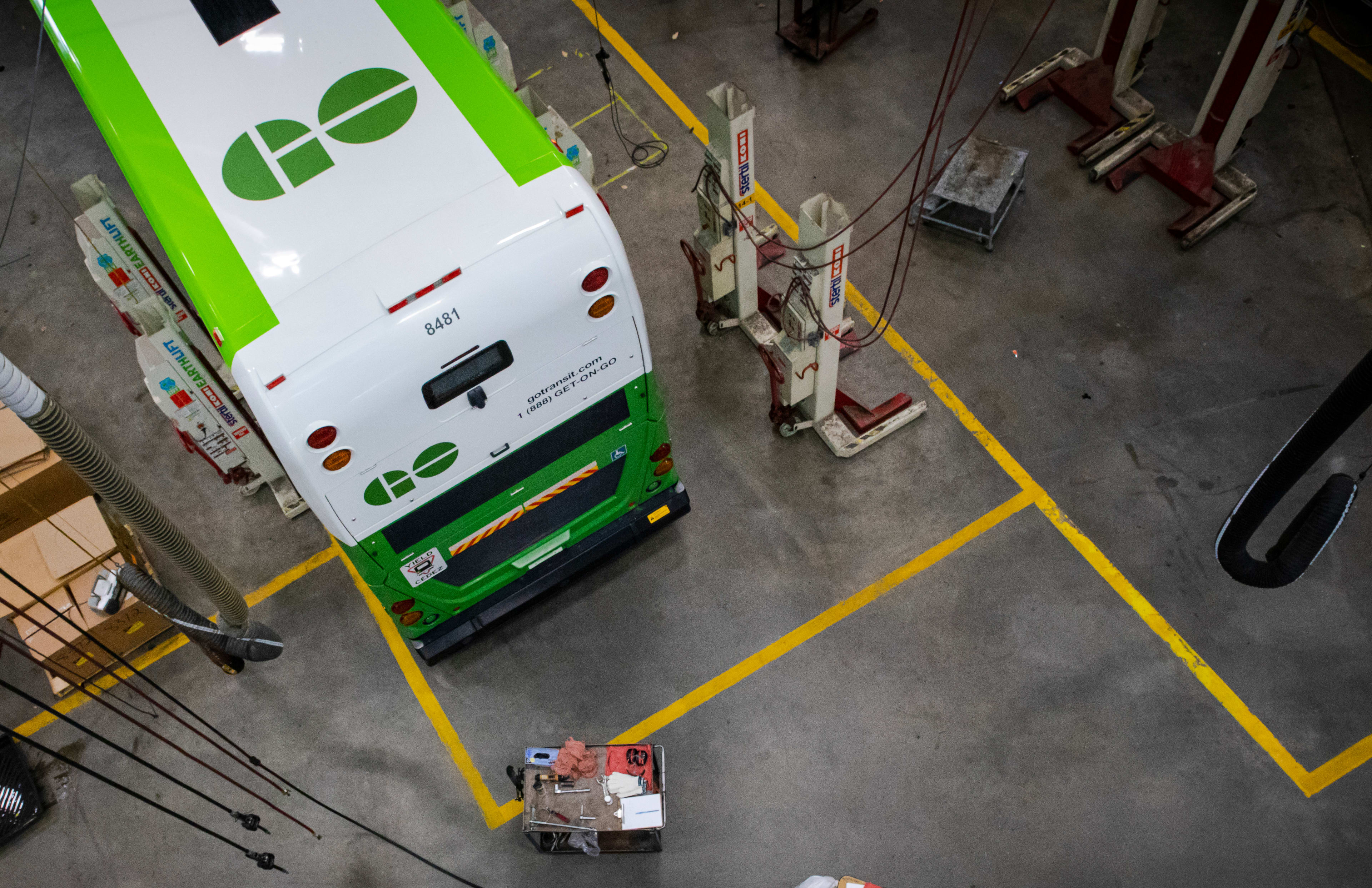 A look down from above, at a worker repairing a bus.