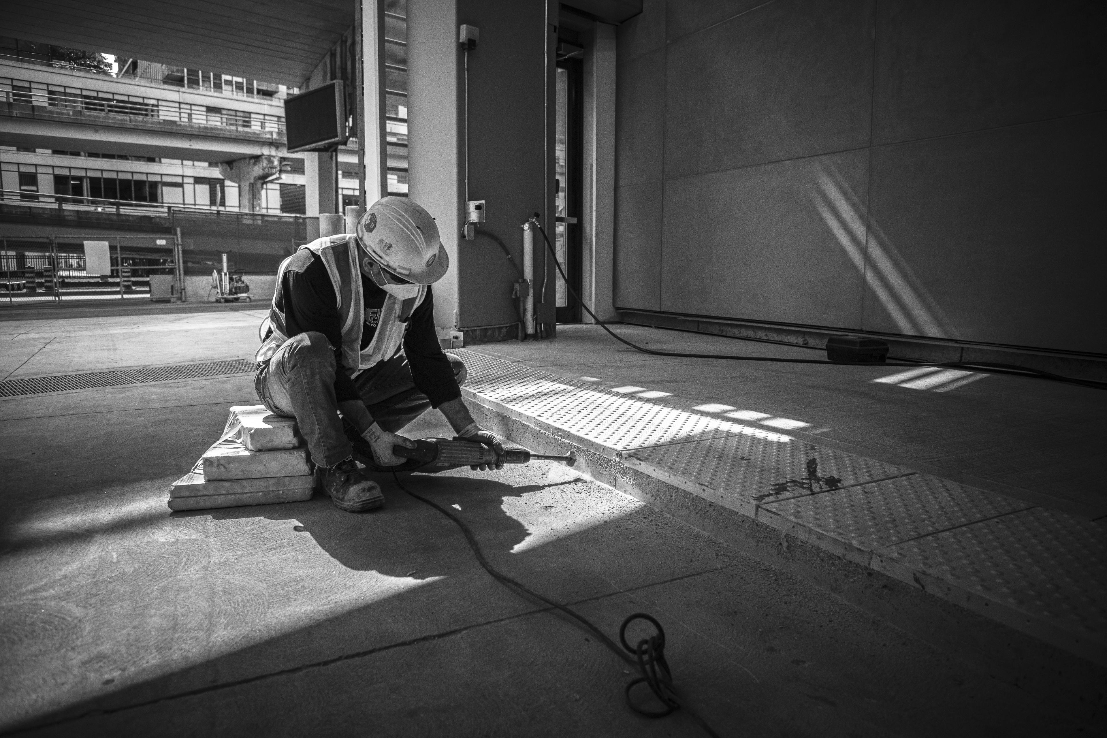 A man uses a grinder on concrete.