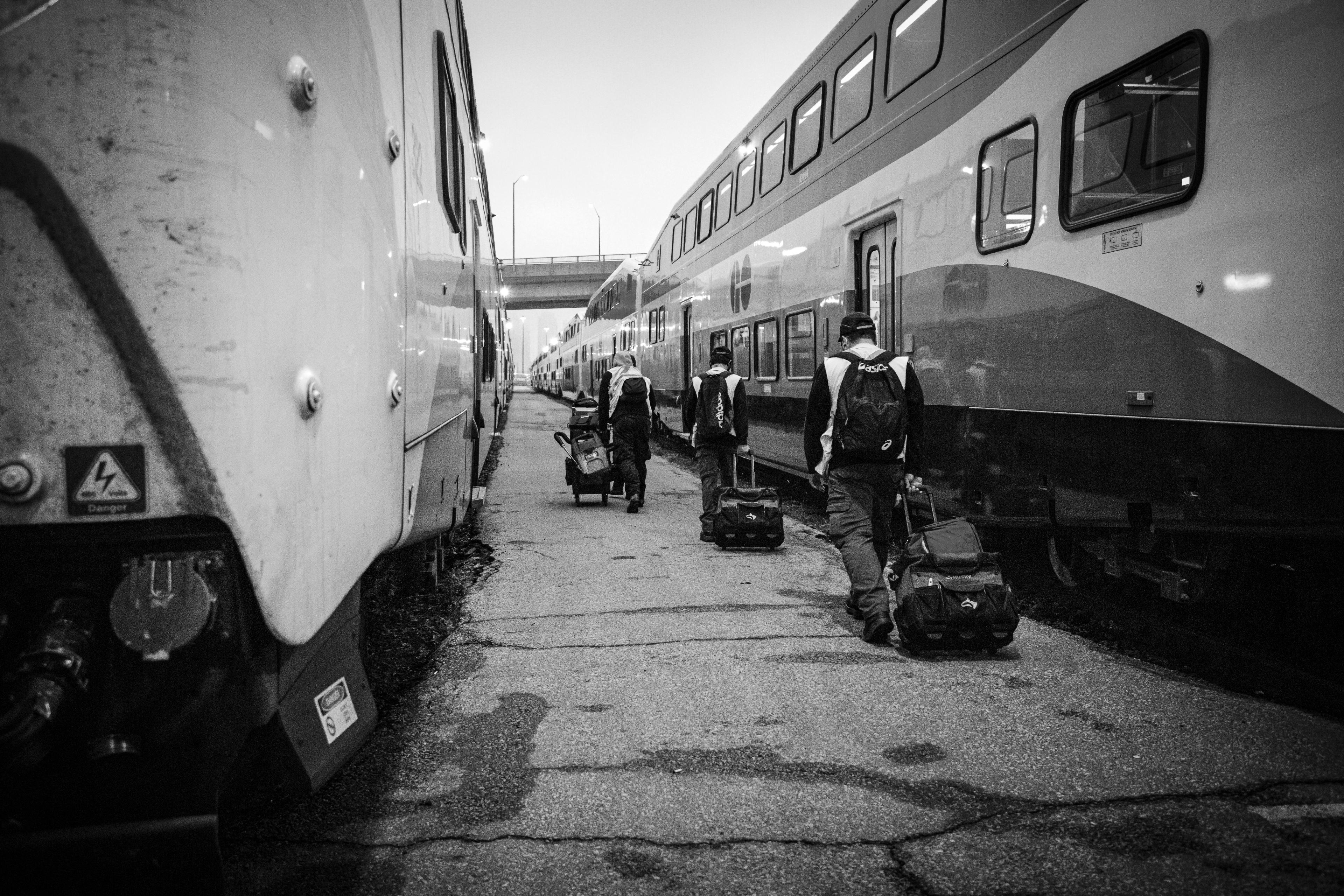 Workers drag work bags along a platform.