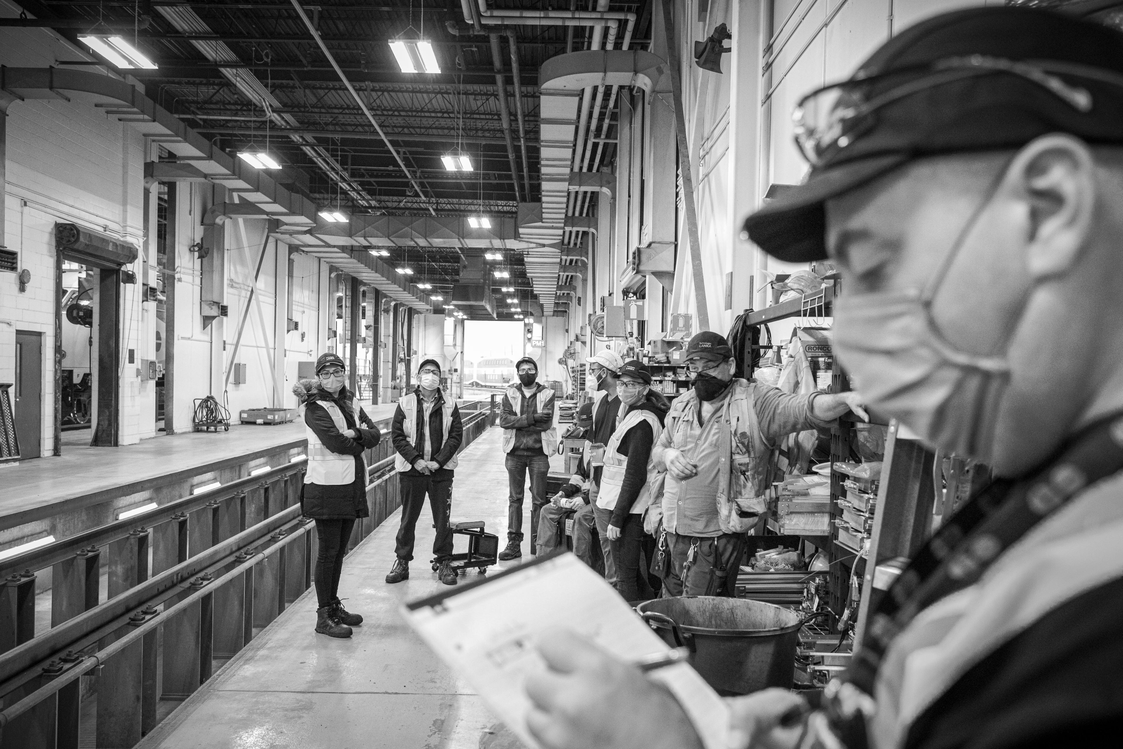 A crew stands and listens to instructions.