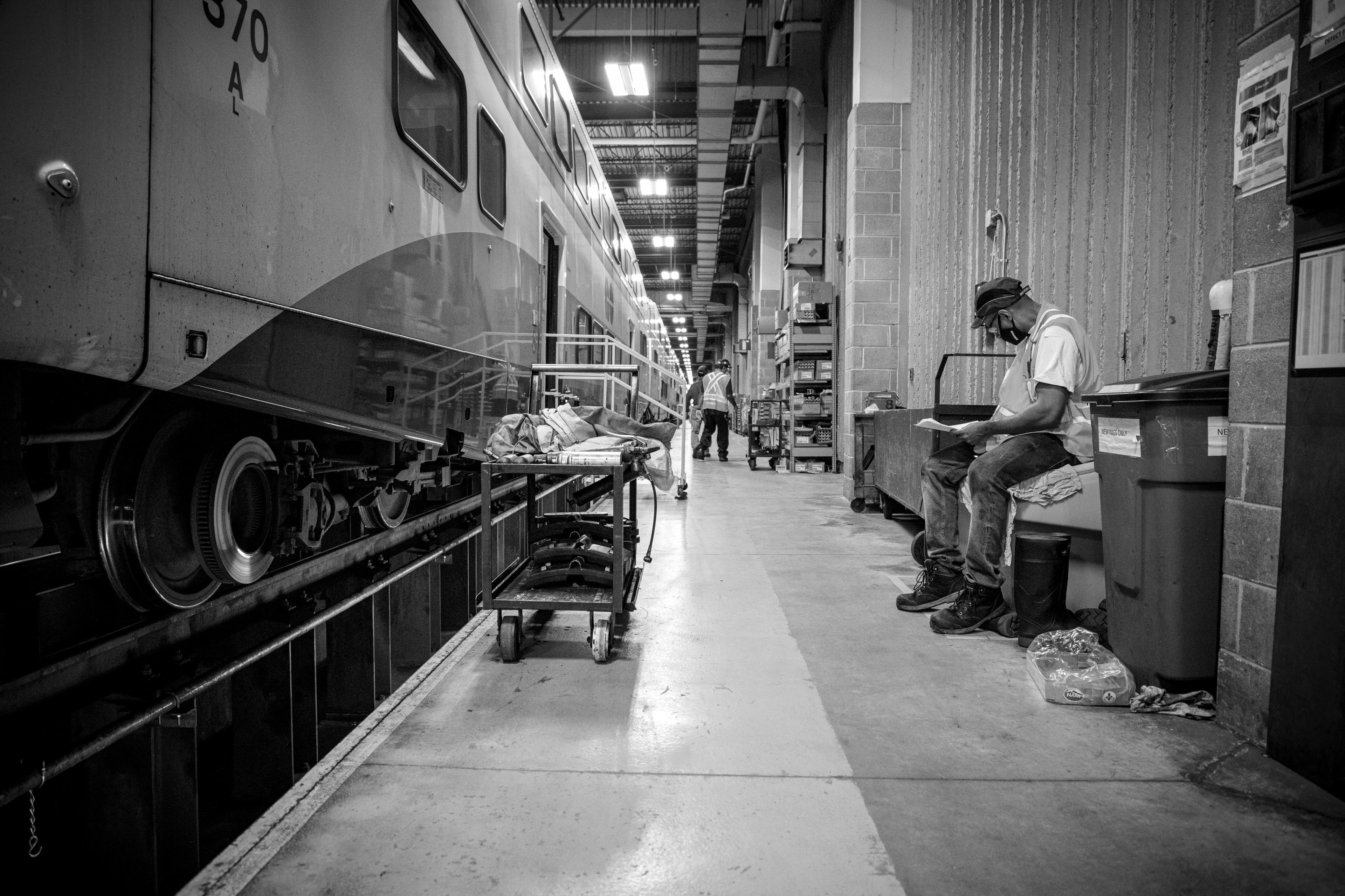 A worker sits next to a train to do some work.