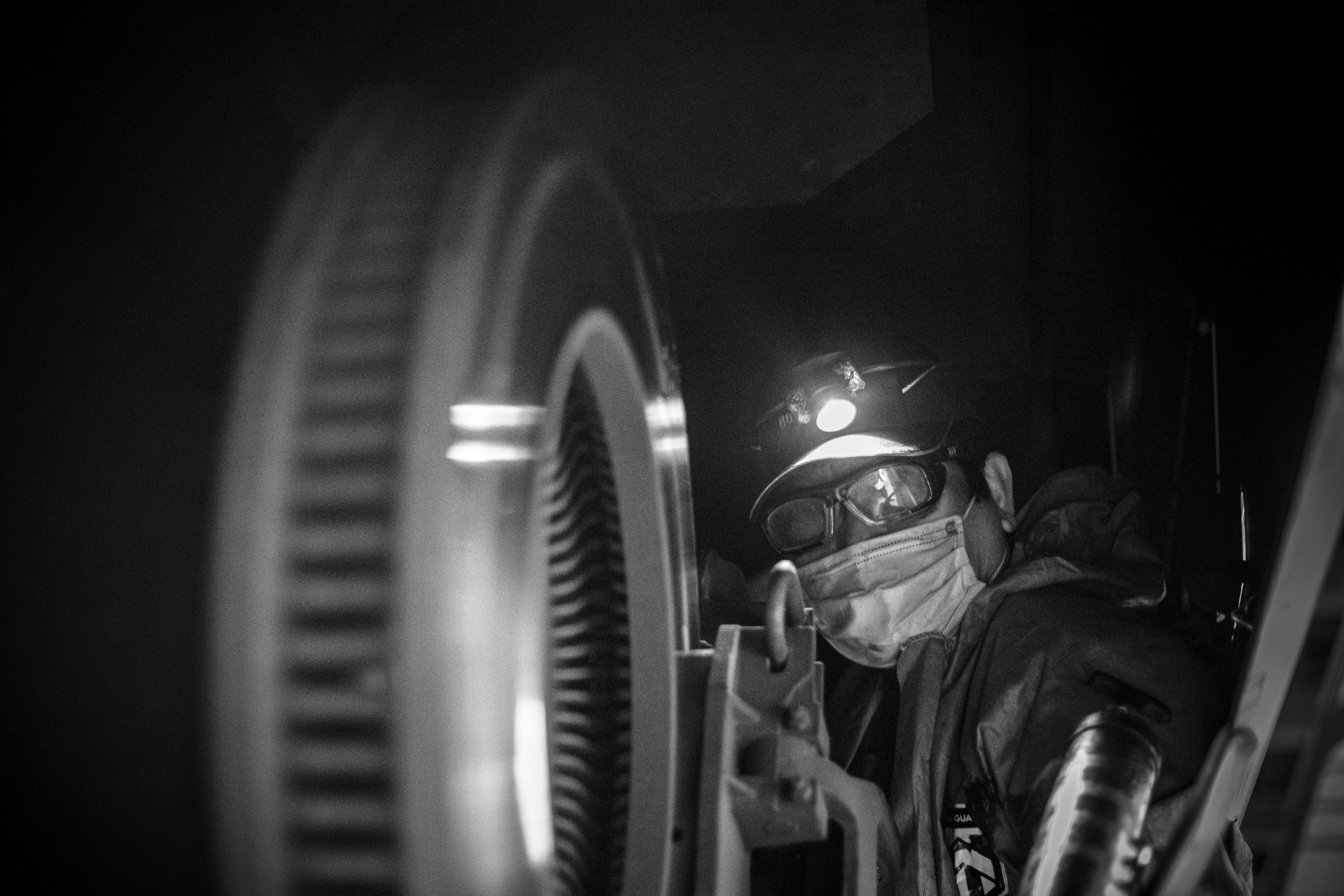 A worker toils under a train.