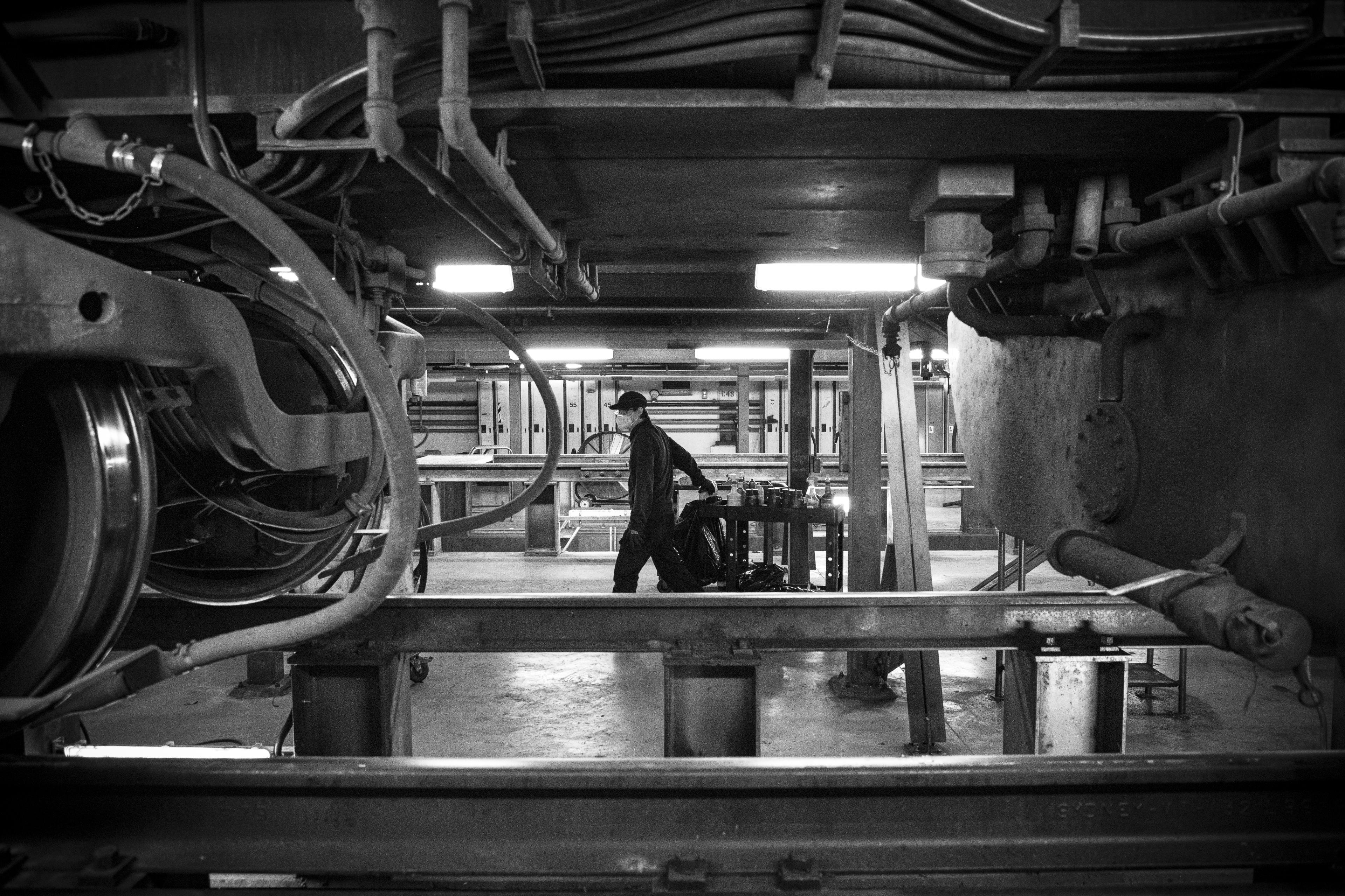 The view from under a train as a worker walks by.