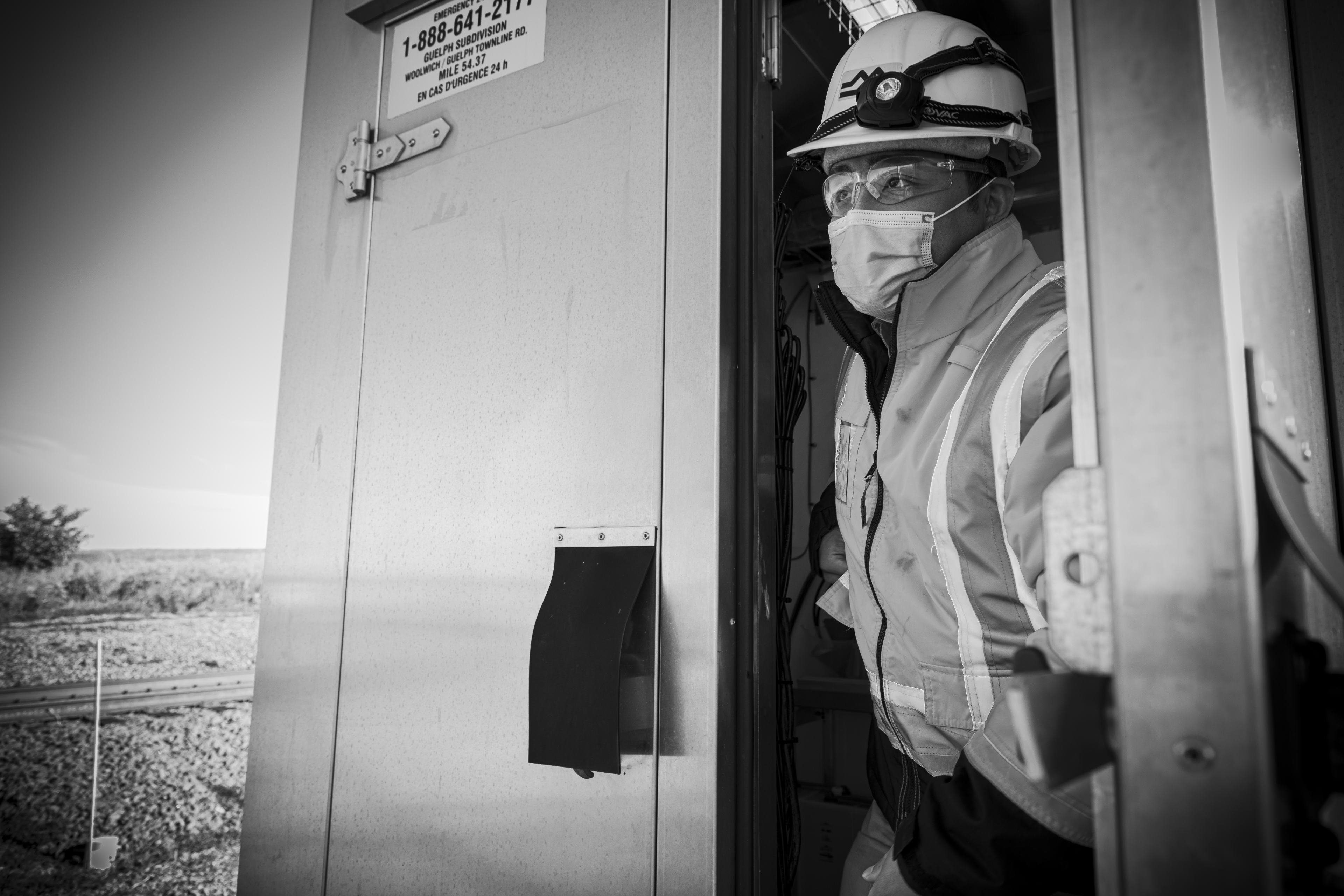 A man looks out from inside a small mechanical shack.