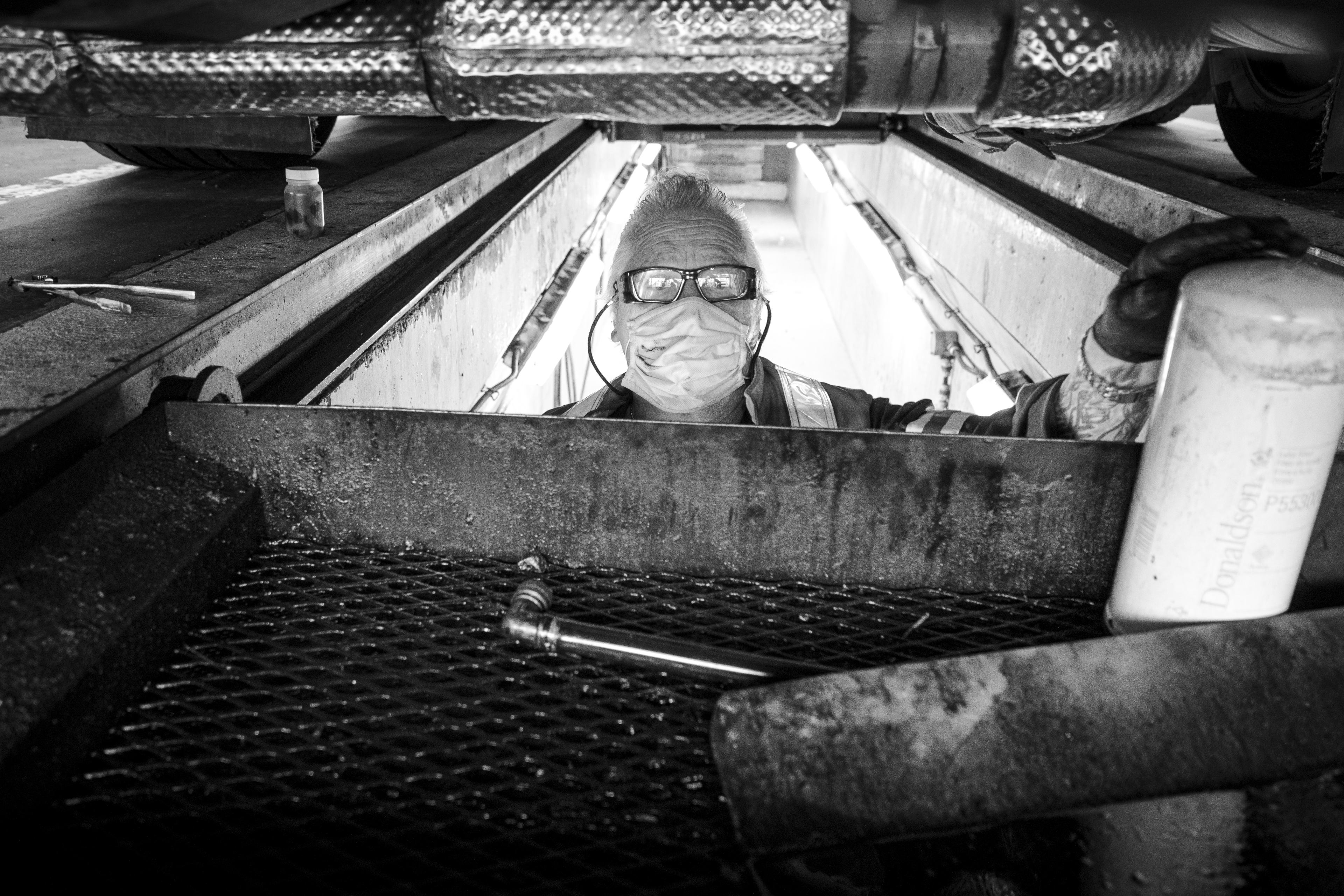 A man poses from under a bus.