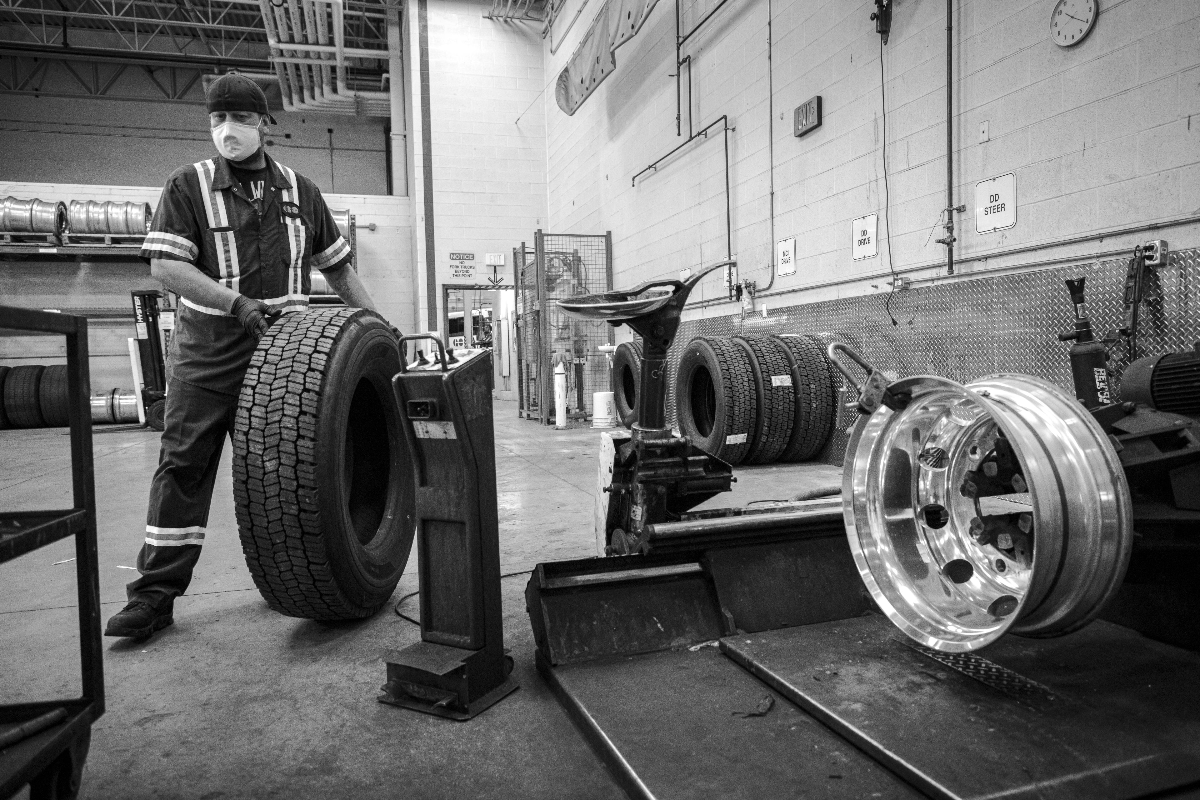 A man rolls a tire along.
