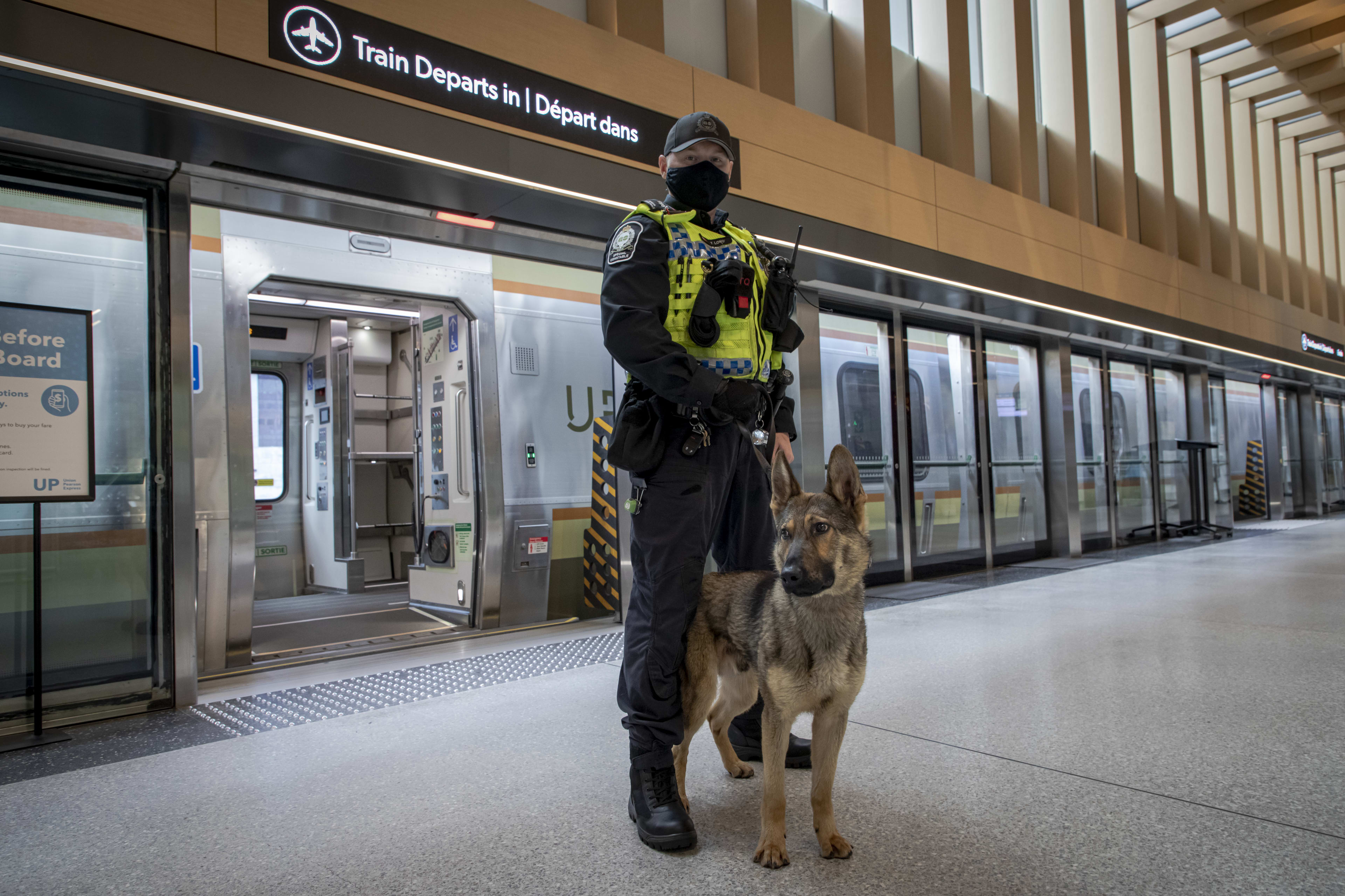 Dog and handler pose for pictures next to an UP Express train.