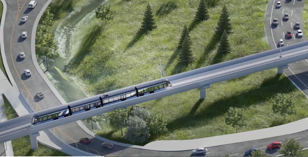 Imagwe shows an LRT on tracks over a highway.