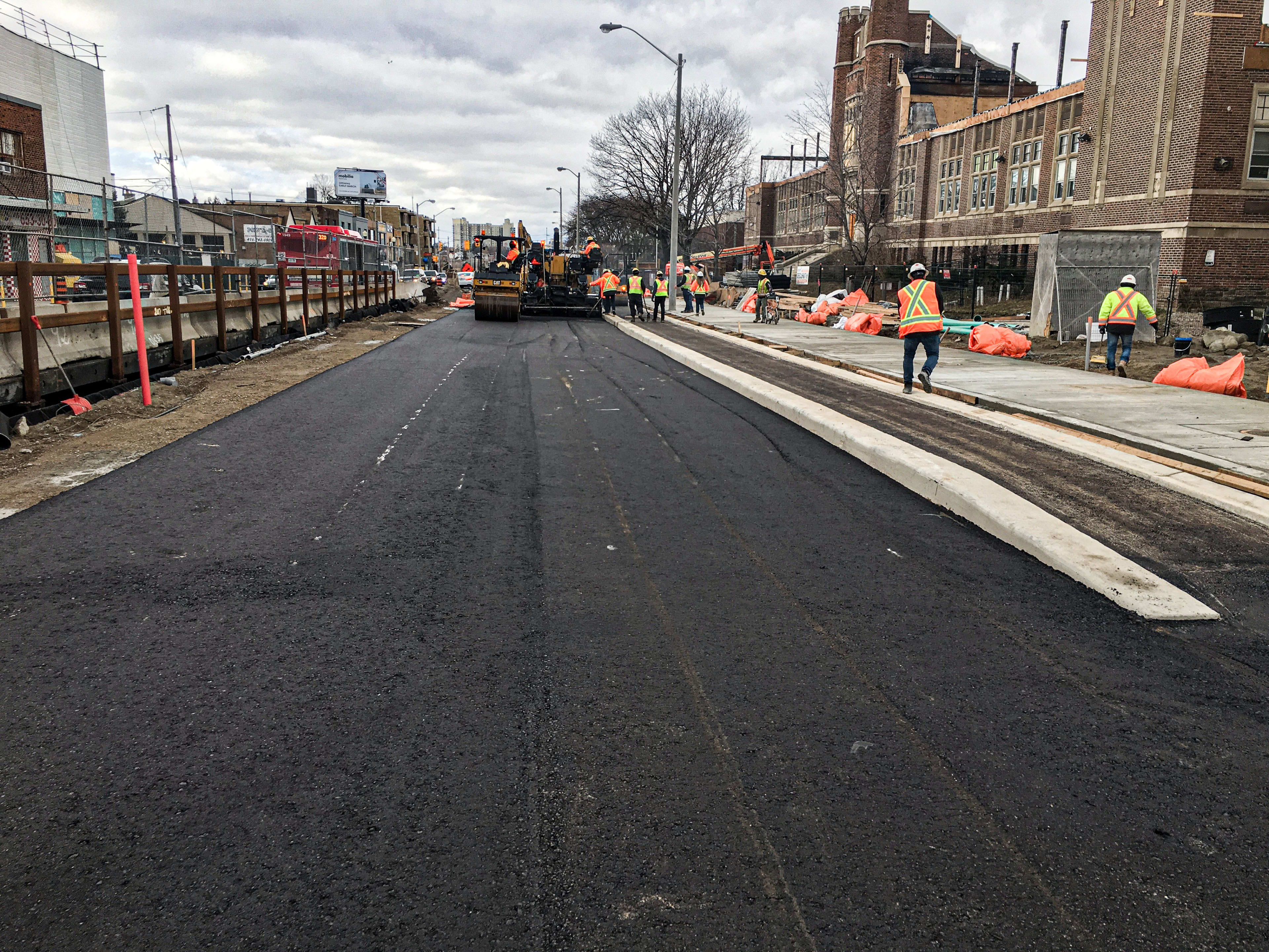 Fresh pavement is put down along a route.