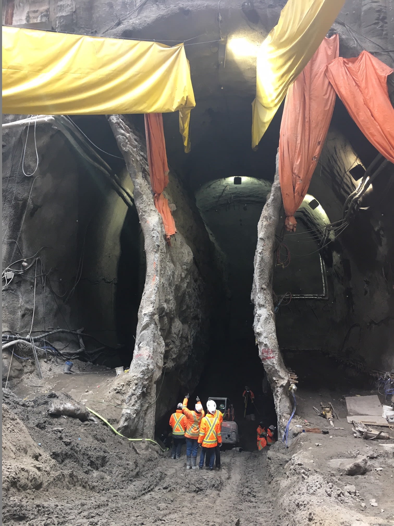Work crews seem small as they stand at the bottom of the cave work and look up toward street level.