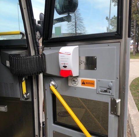 A dispenser is shown attached to a bus door.