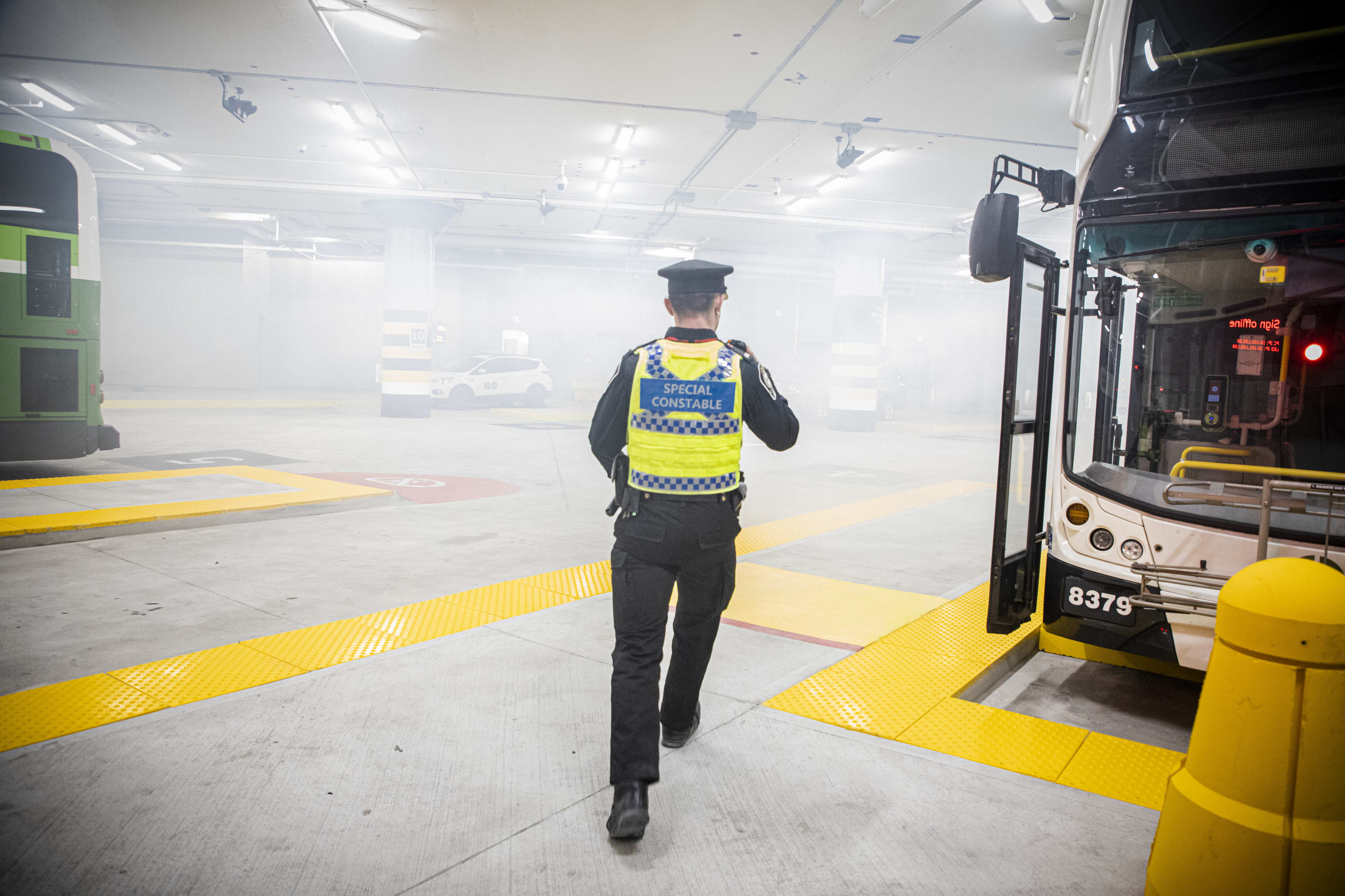 As simulated smoke fills the bus parking area, a Metrolinx Transit Safety officer runs past a veh...