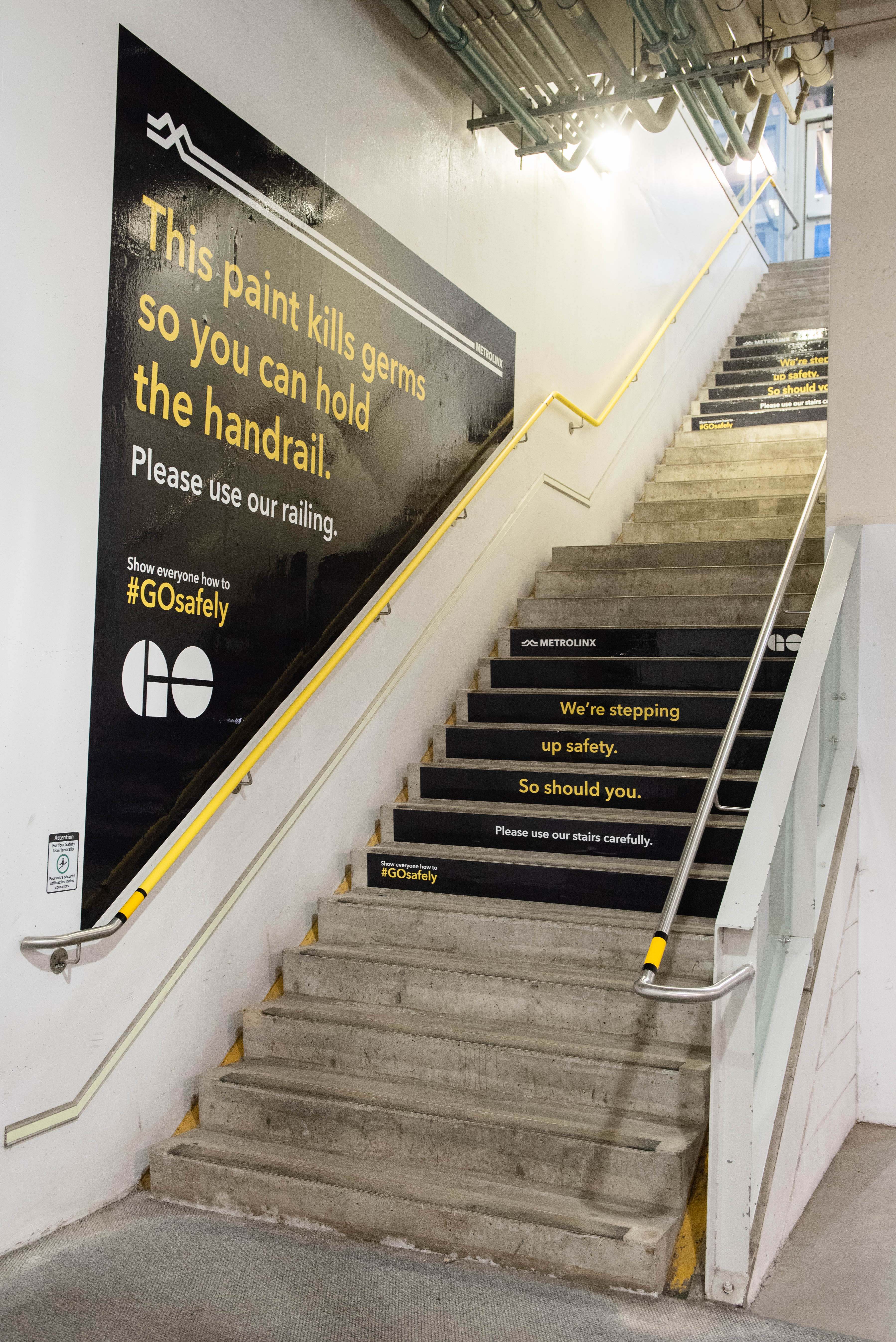 Stairs are shown with warning signs reminding customers to hold the handrails and watch their ste...