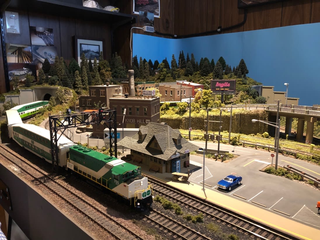 A model GO Train rounds a bend on an elaborate miniature Toronto railroad track.