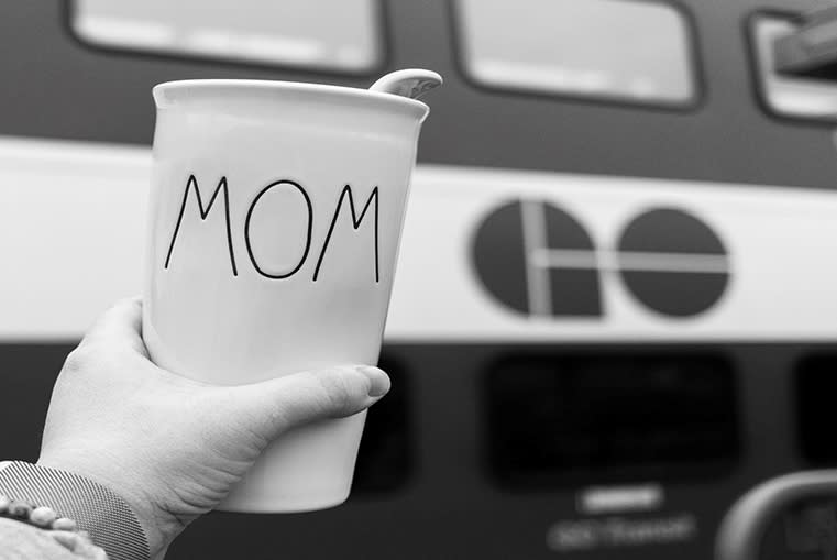 someone holding up a coffee cup next to a GO train.