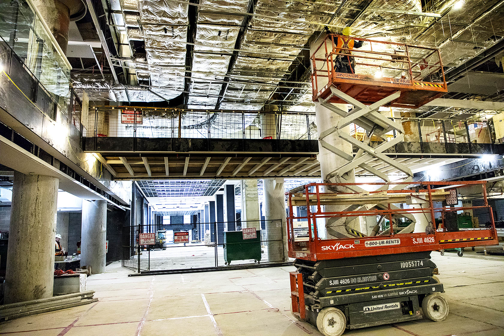 A cheery-picker hoists a worker toward the ceiling.