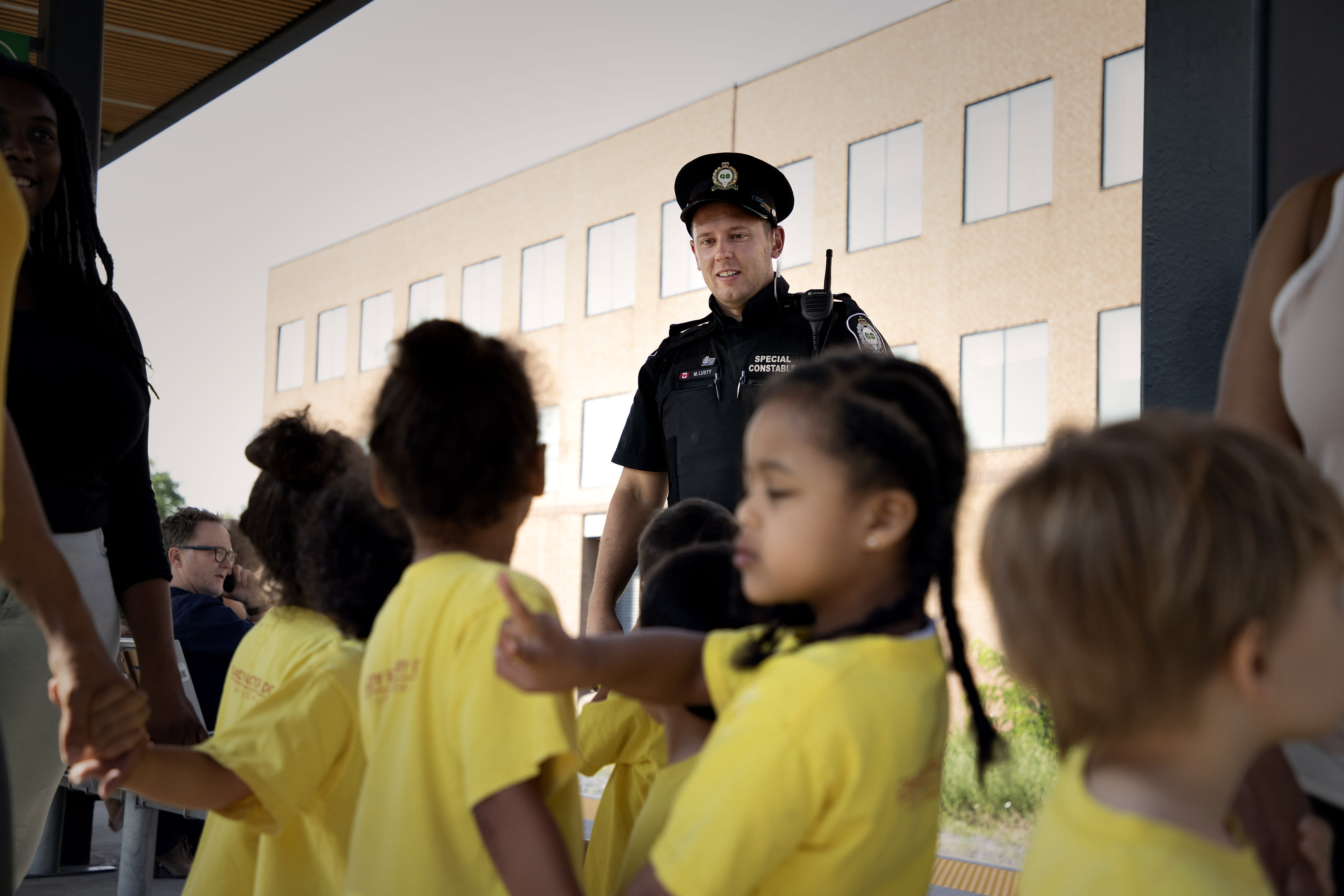 A transit safety officers talks to a group of children gathered on the platform.
