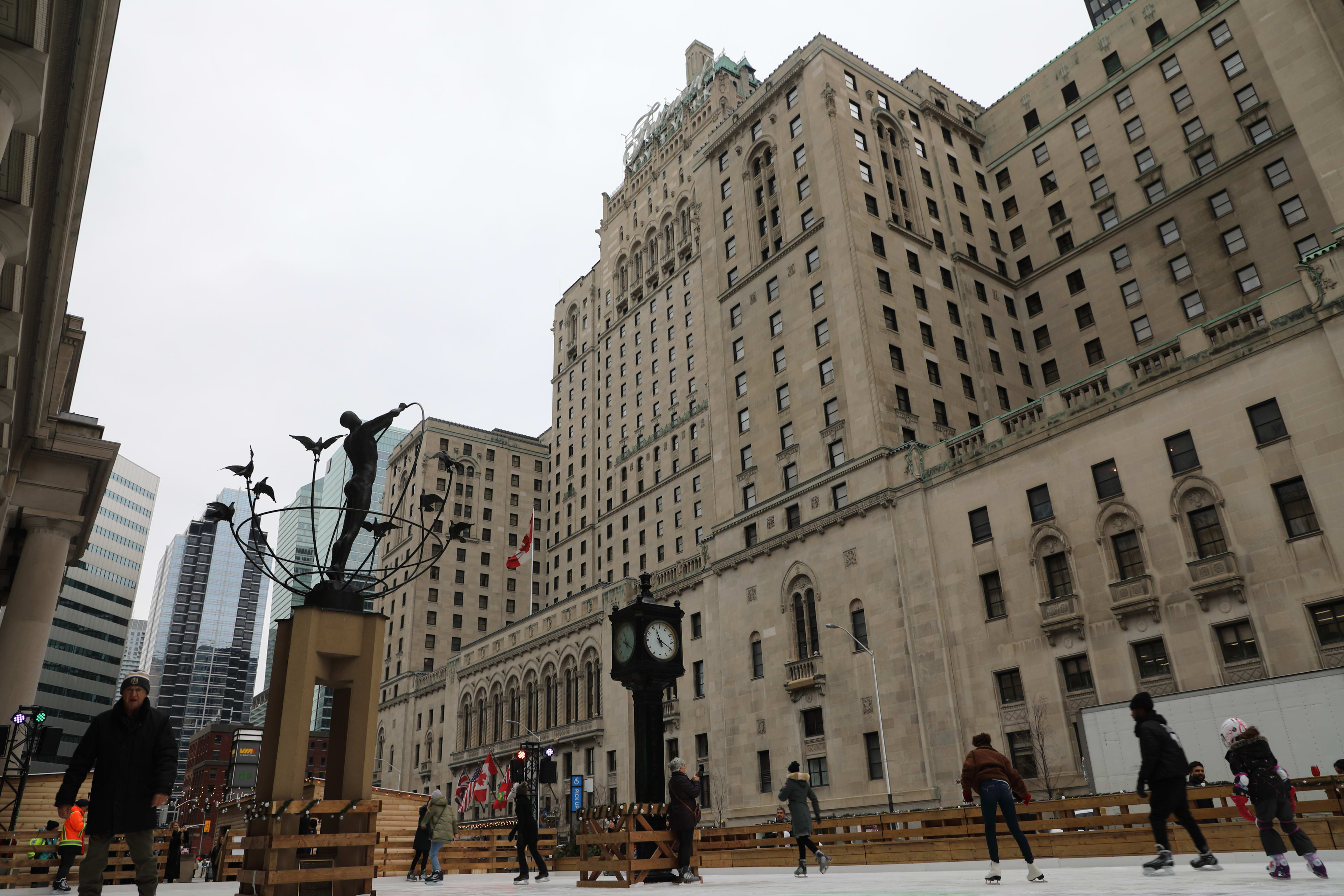 People skating on the ice rink outside of Union Station with the Royal York standing in the backg...