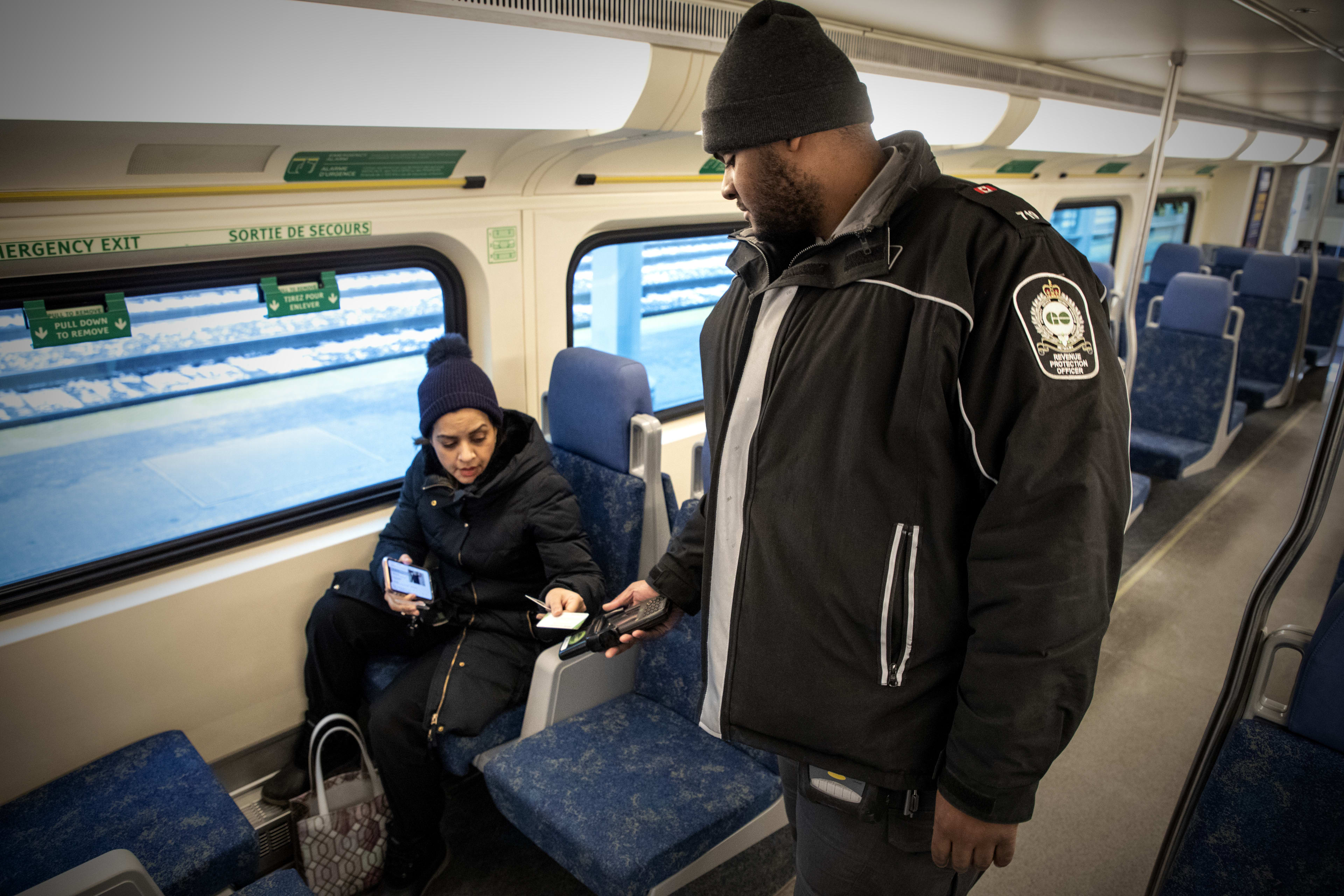 An officer checks a PRESTO card, held out by a customer.