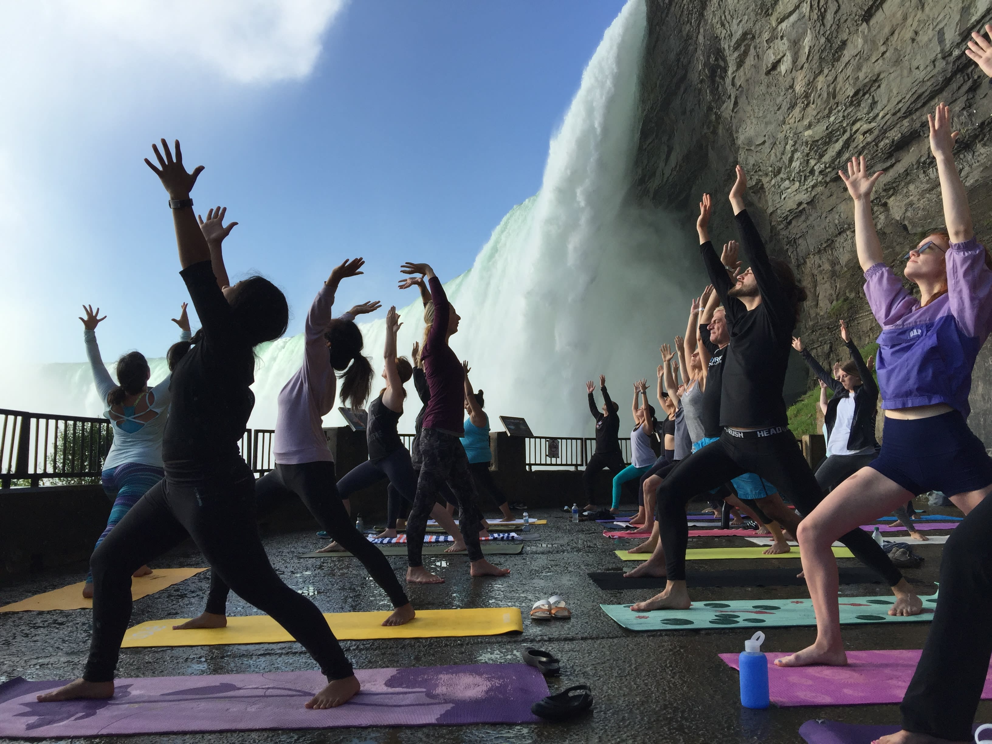 Students stretch while water from the Falls cascades behind them.