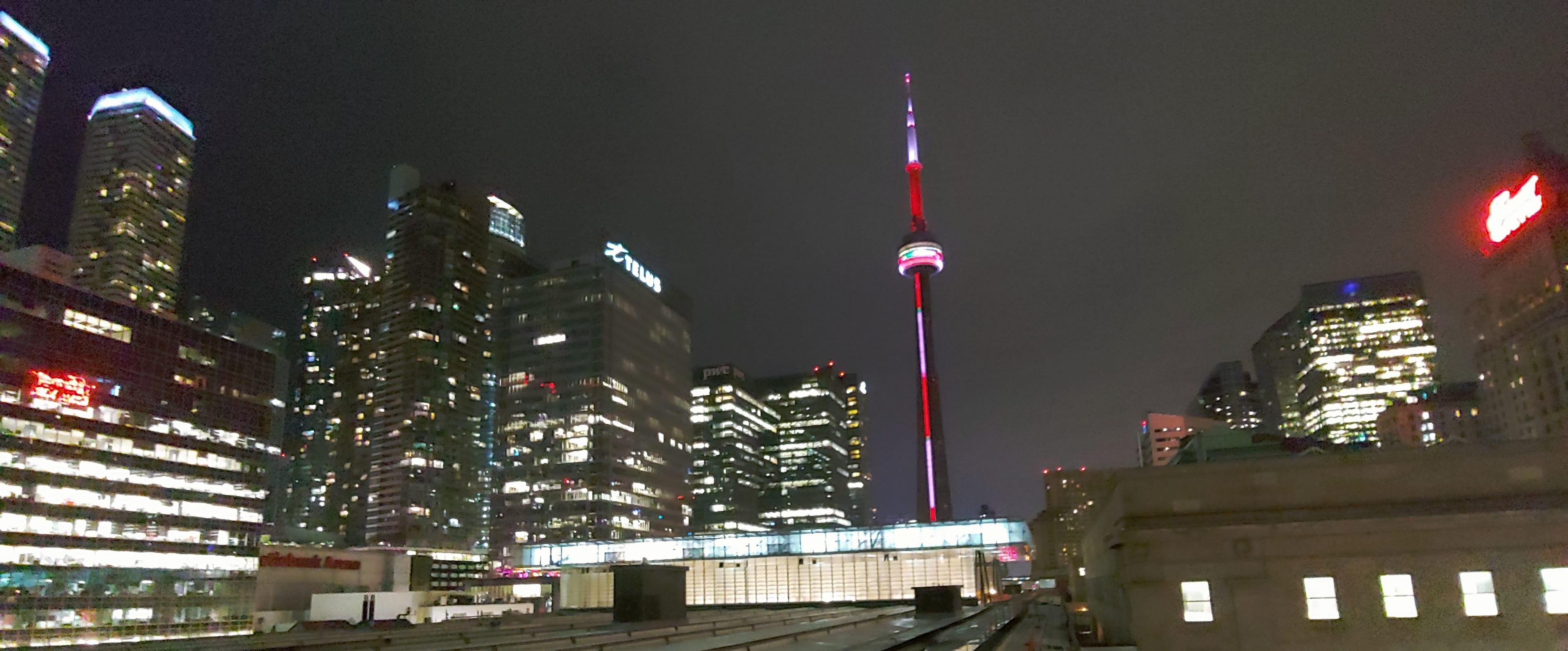 Union Station is lit up against a dark sky, with nearby office buildings also bright.