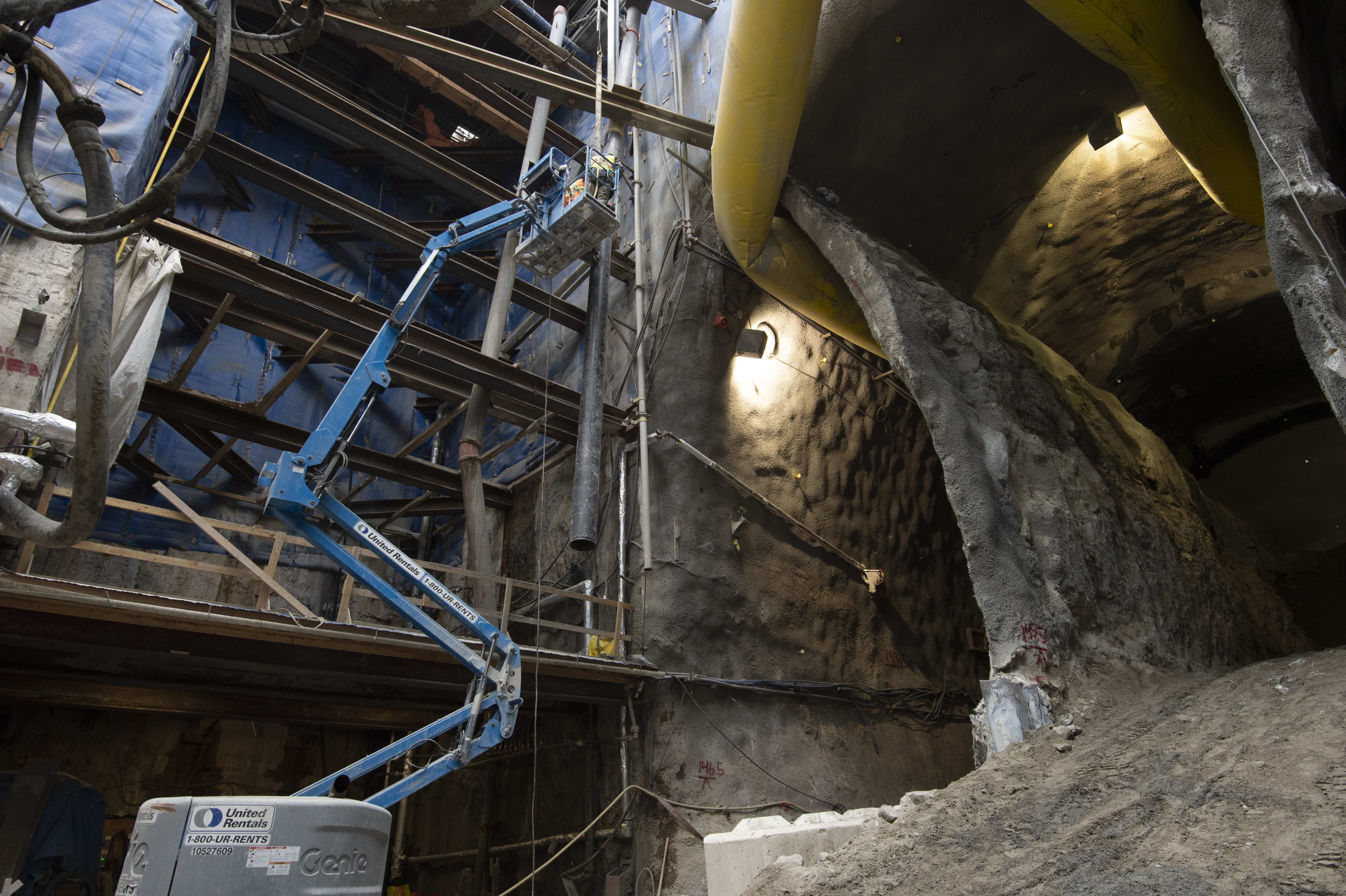 A crane works inside a massive cavern that's been dug out below an active part of the city. Shown...