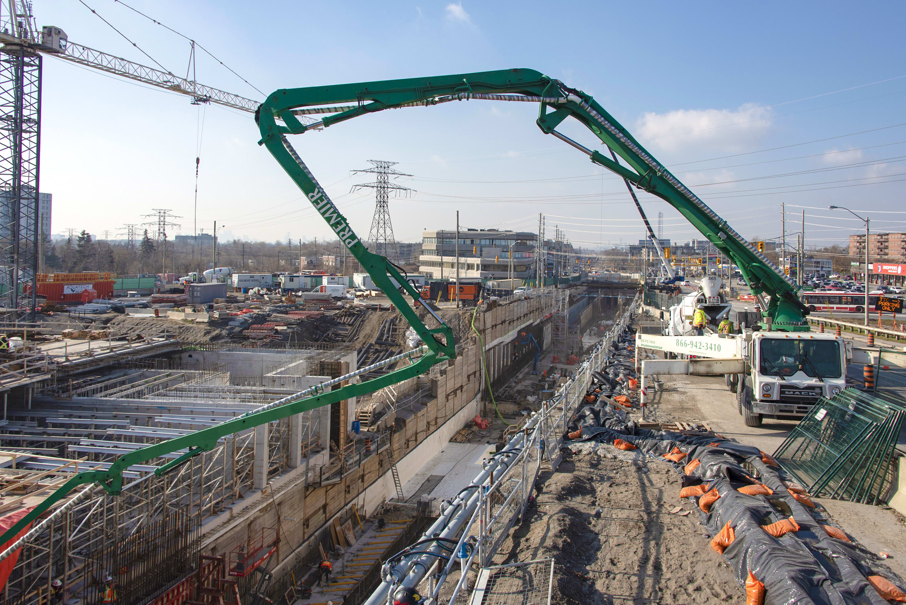 A very long crane reaches far to deliver concrete at a job site.