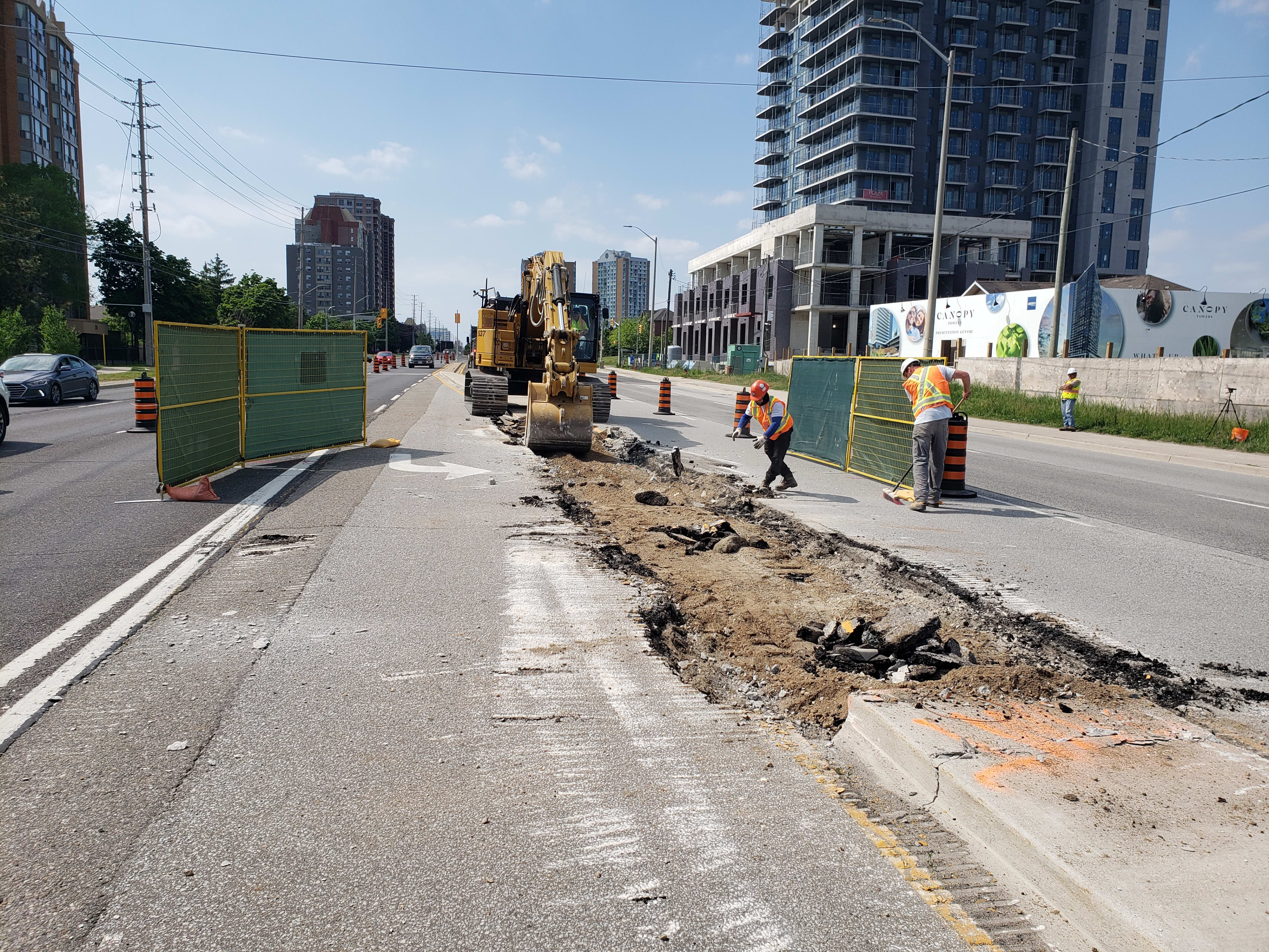 Workers clear debris from a street after a median has been removed.