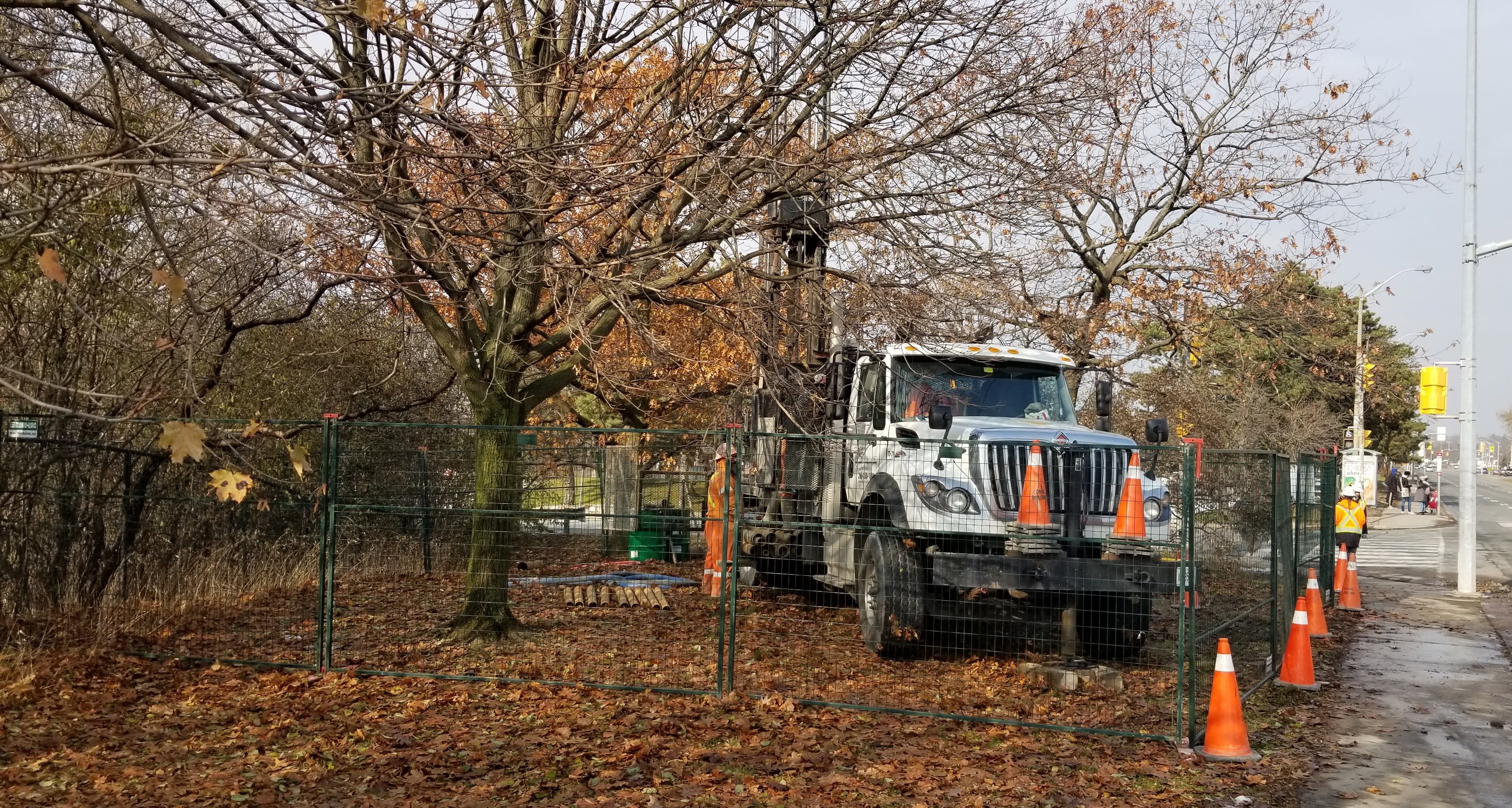 A drilling truck - about as big as a fire truck - sits beside a roadway.