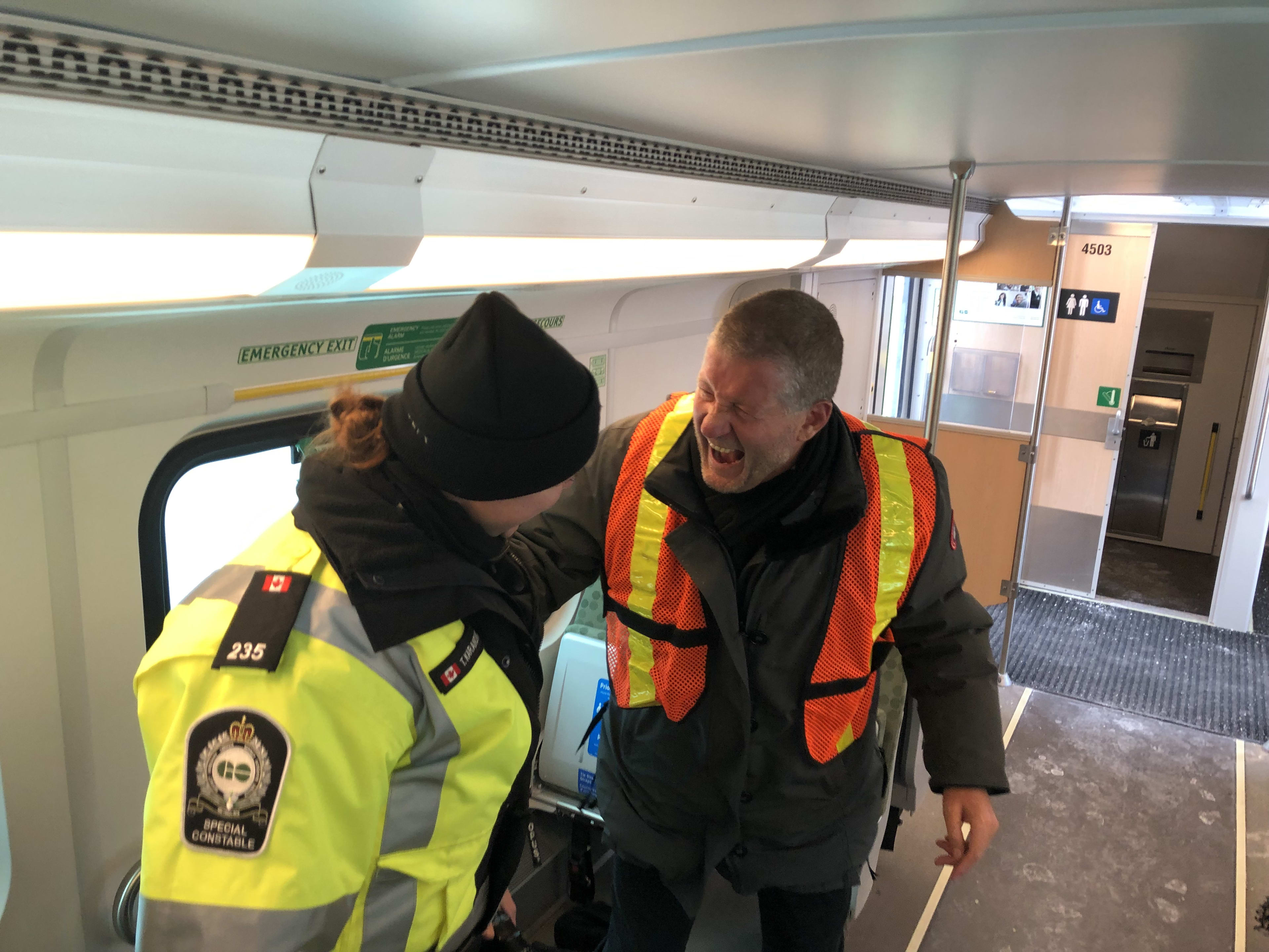 Officer Karanovic and Metrolinx CEO Phil Verster stand and share a laugh together while onboard a...