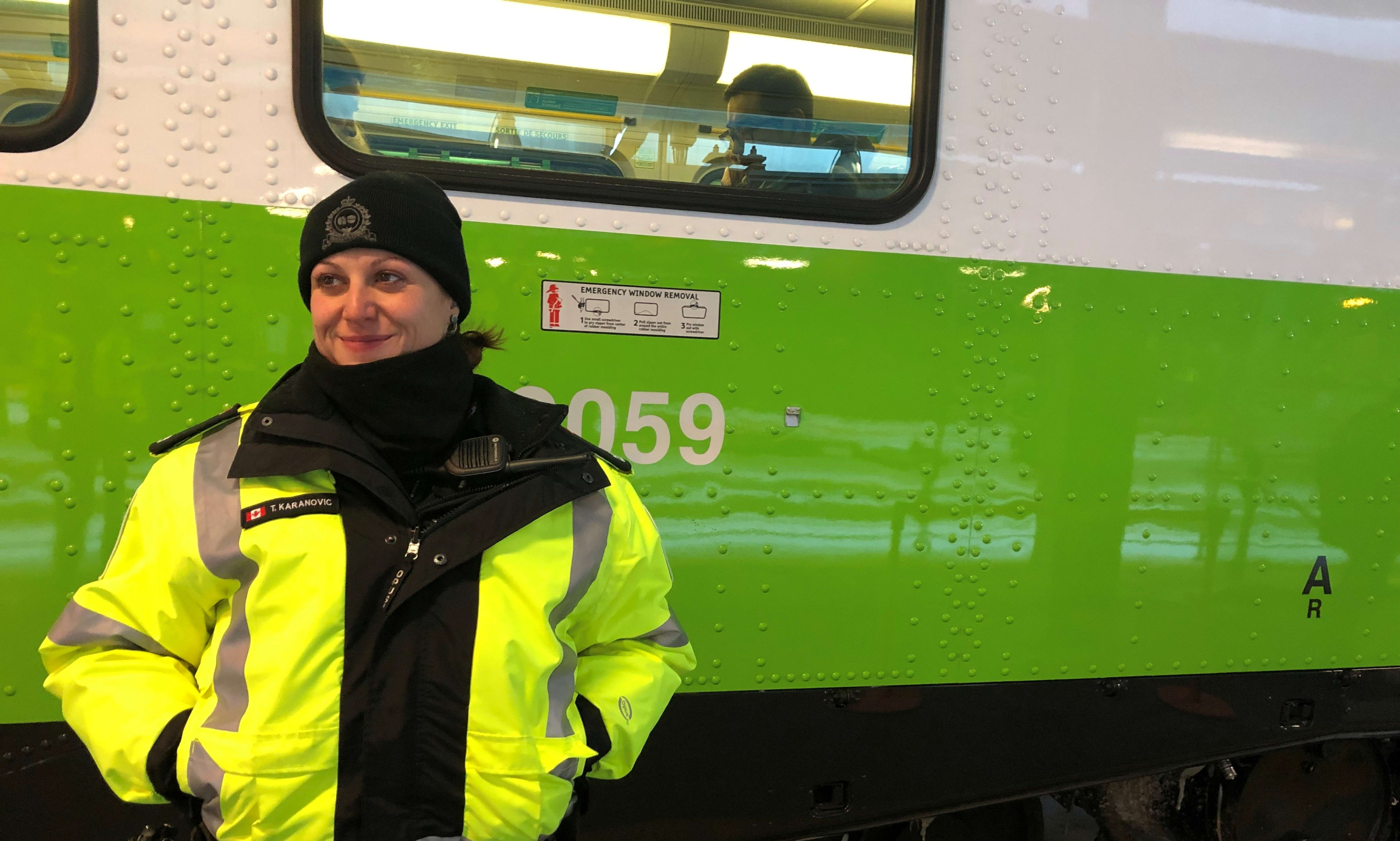 Transit officer Tihana Karanovic smiles, as she stands, hands in warm pockets, in front of a GO t...