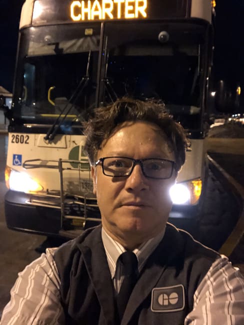 An image of a bus driver in front of a bus.