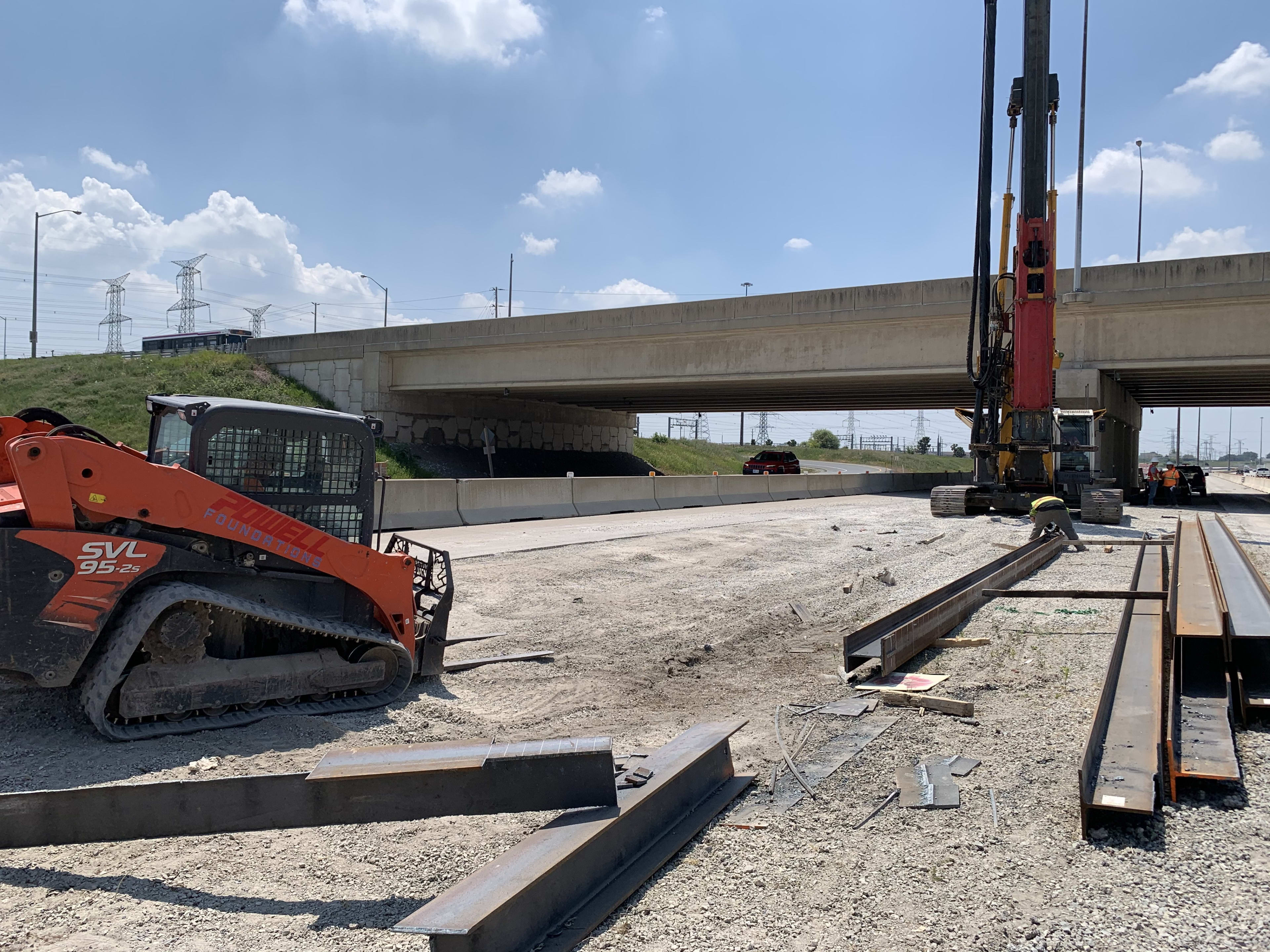 A tractor waits near a machine working on pilings.