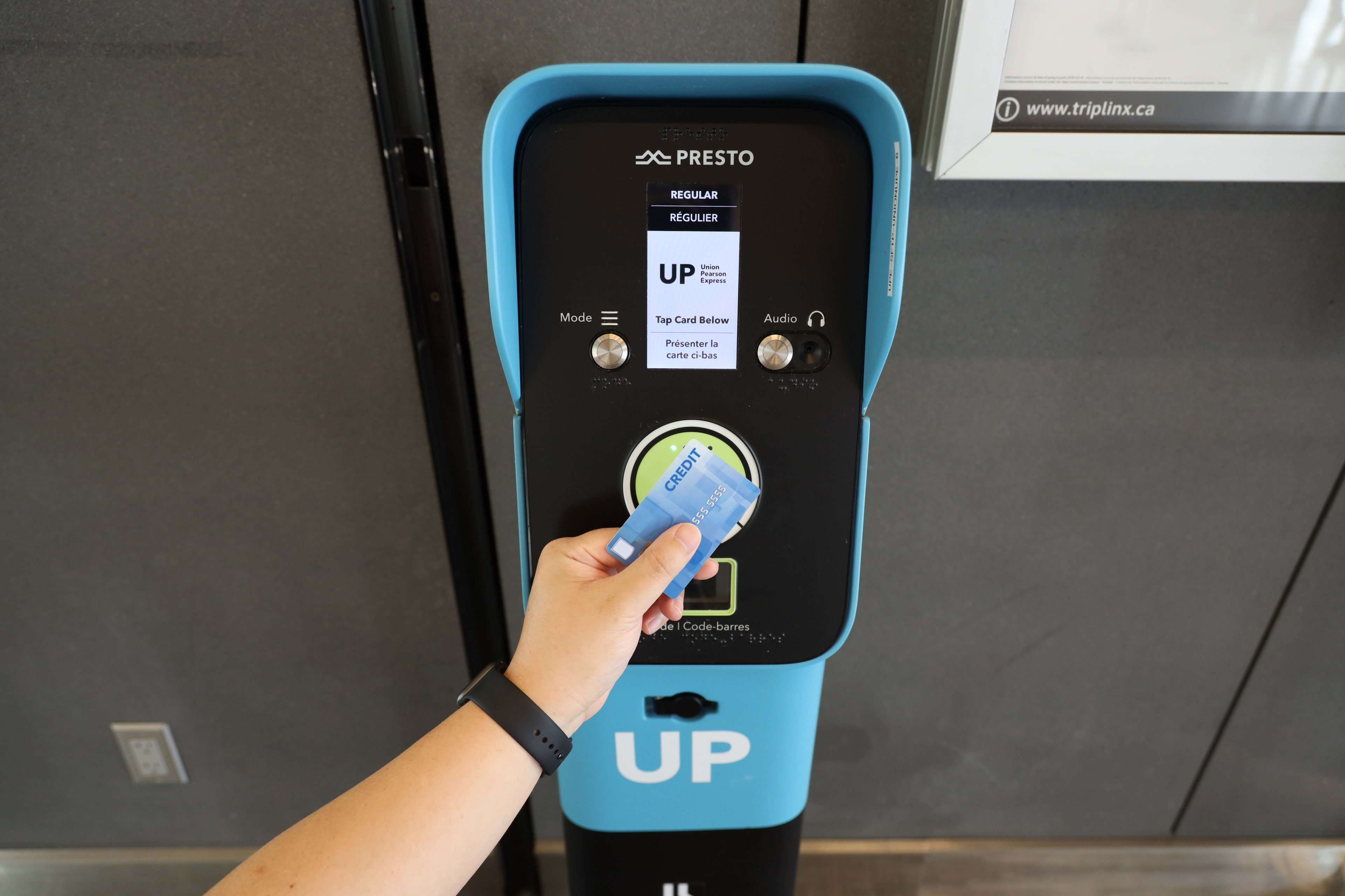 a person taps a blue credit card on the UP Express machine