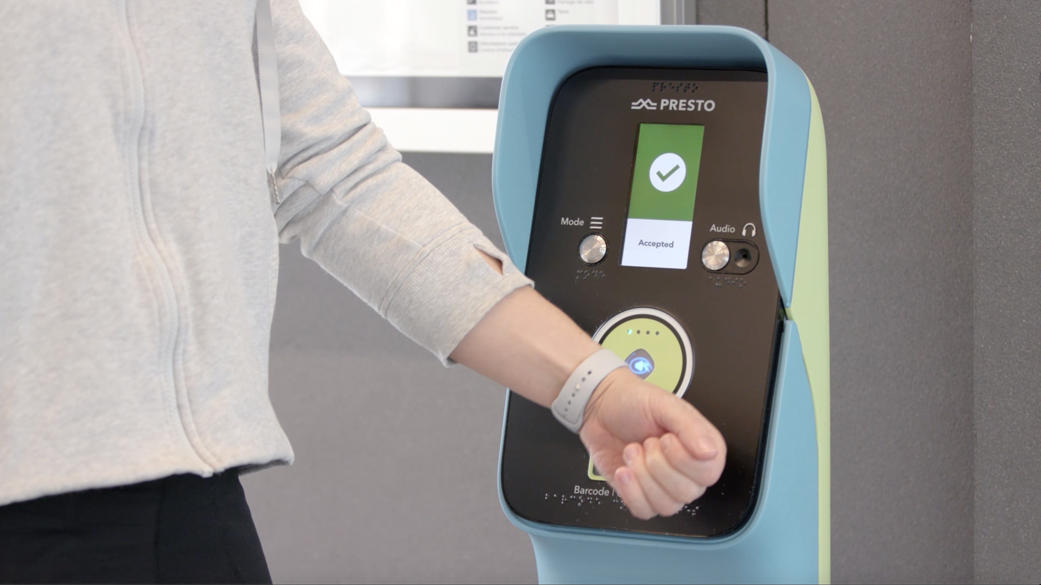 A person taps their smart watch on the UP Express terminal to pay.