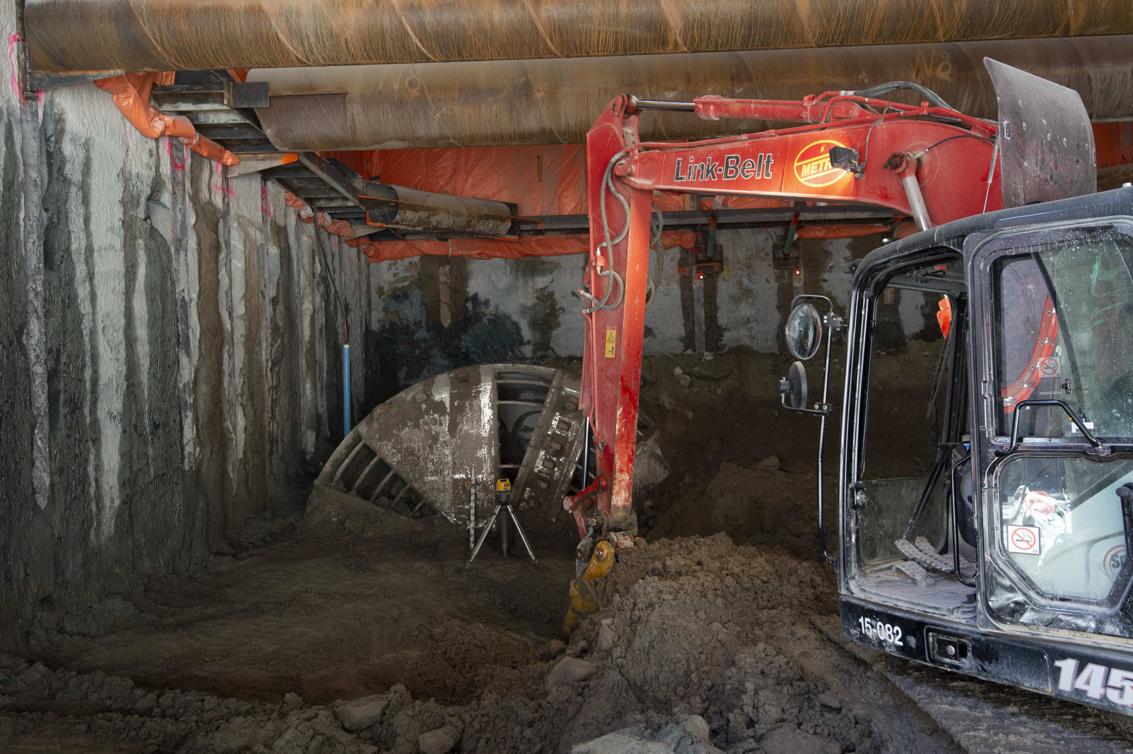 A tractor pulls dirt from a large boring machine.