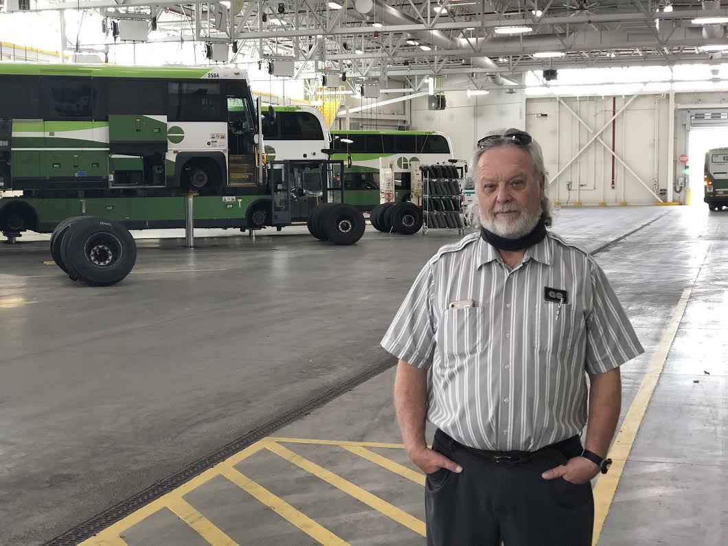 GO Bus driver stands in the garage with buses int he background