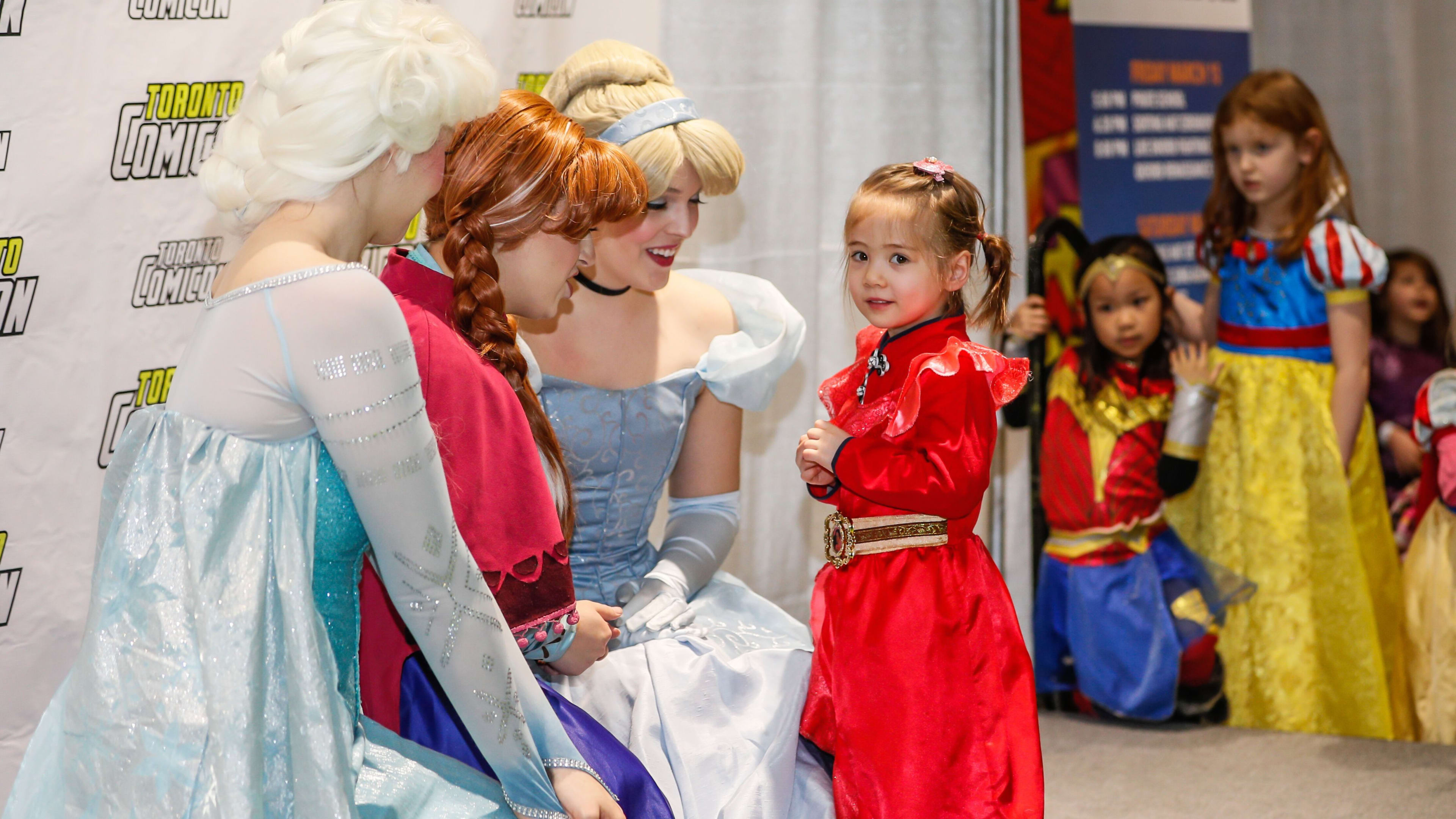 young kids in princess costumes pose with princesses