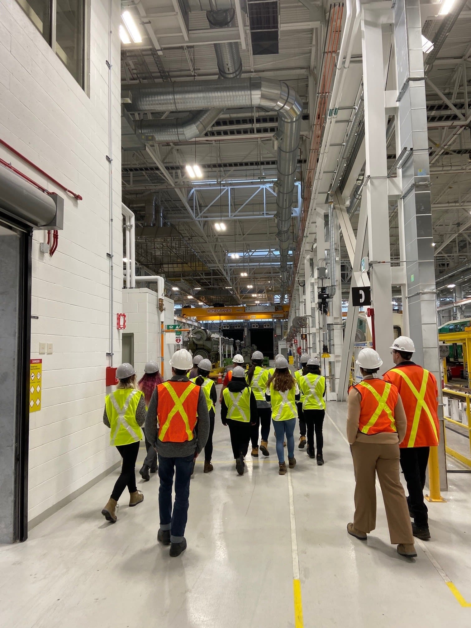 A group walks through the inside of a large maintenance facility.