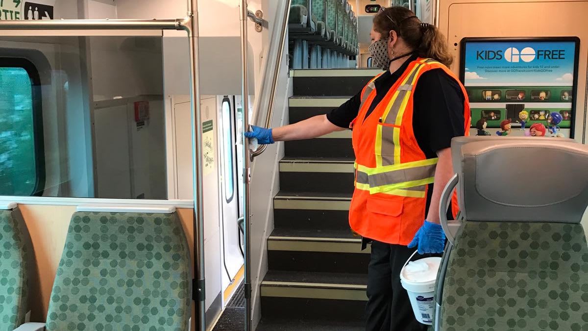 cleaning staff wiping down the inside of a GO Train